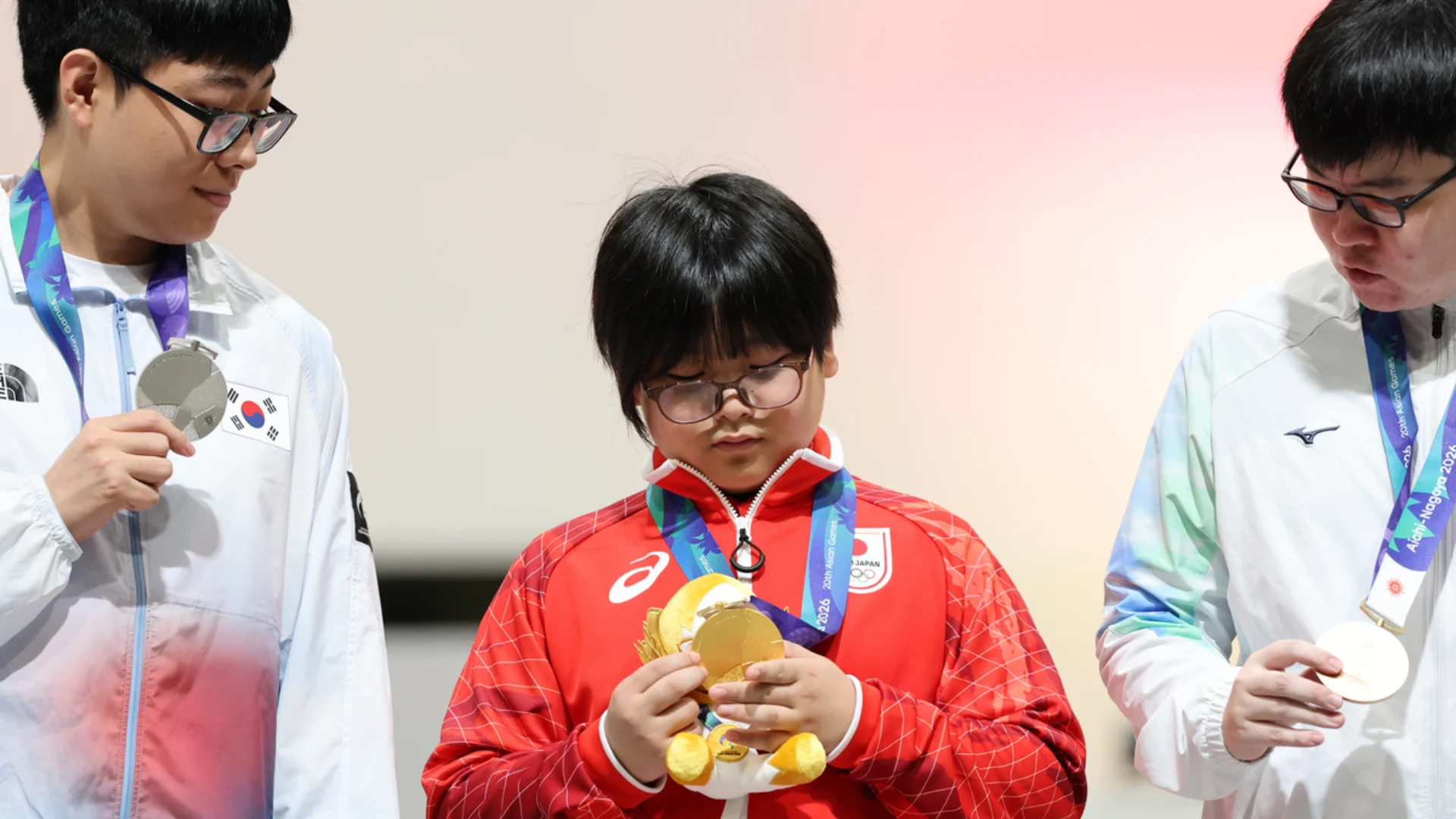 Yuki Kurihara holds his Asian Games gold medal between South Korean and Chinese Taipei medalists.