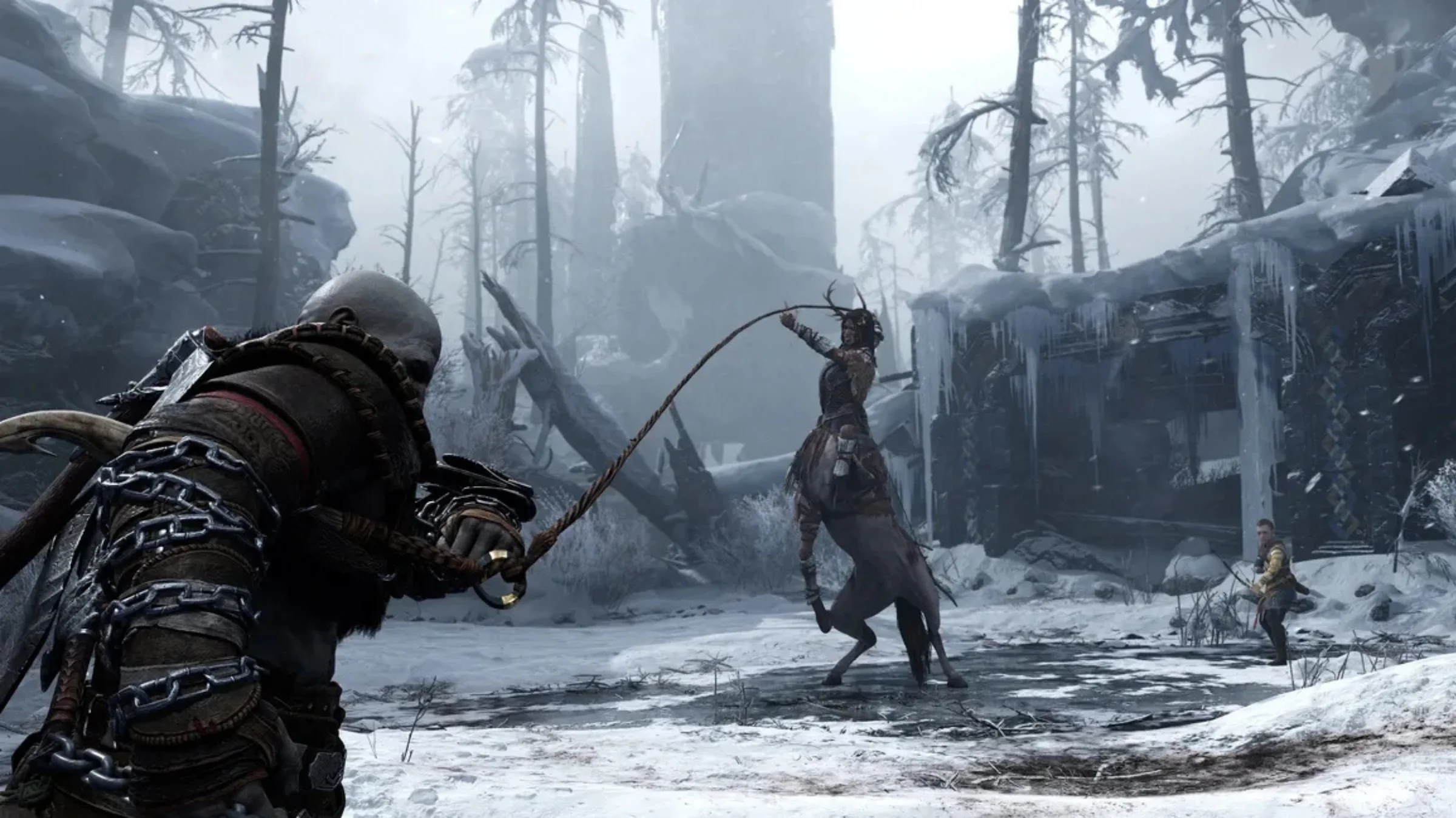 Kratos lashes a chained weapon at an enemy in a frozen forest while Atreus stands nearby.