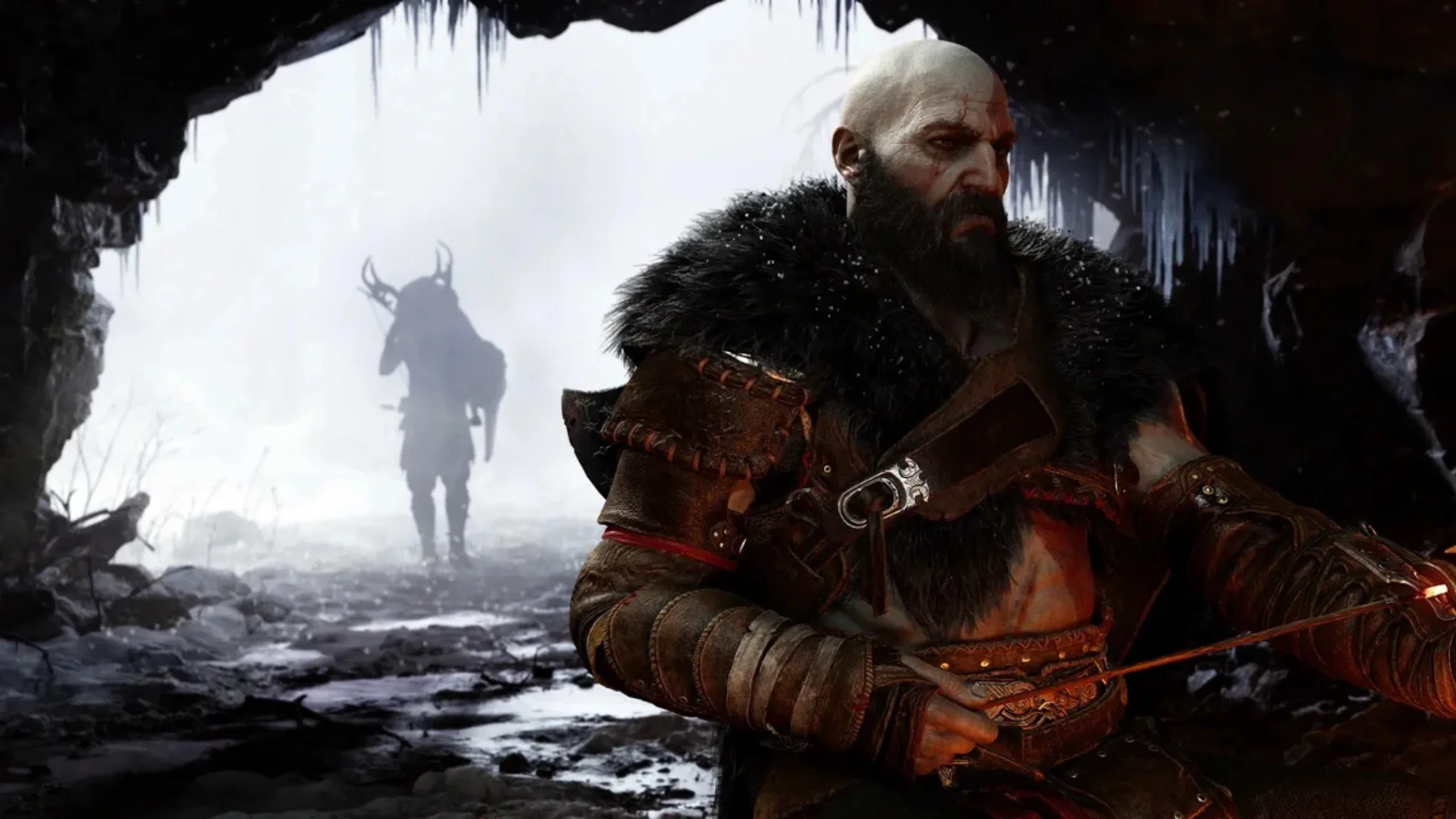 Kratos stands inside a dark icy cave while a figure appears in the snowy distance behind him.