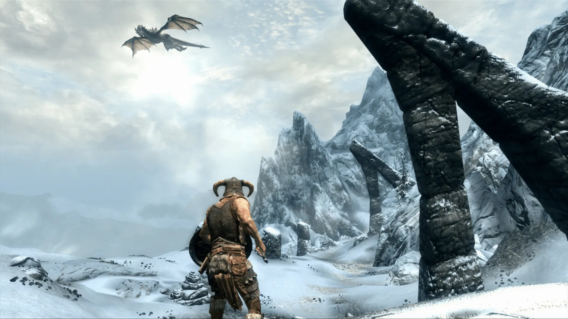 A warrior looks toward a dragon flying over snowy mountains in Skyrim.
