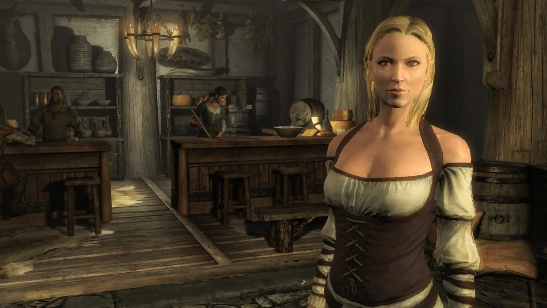 A blonde tavern character stands in front of the bar inside a Skyrim inn.
