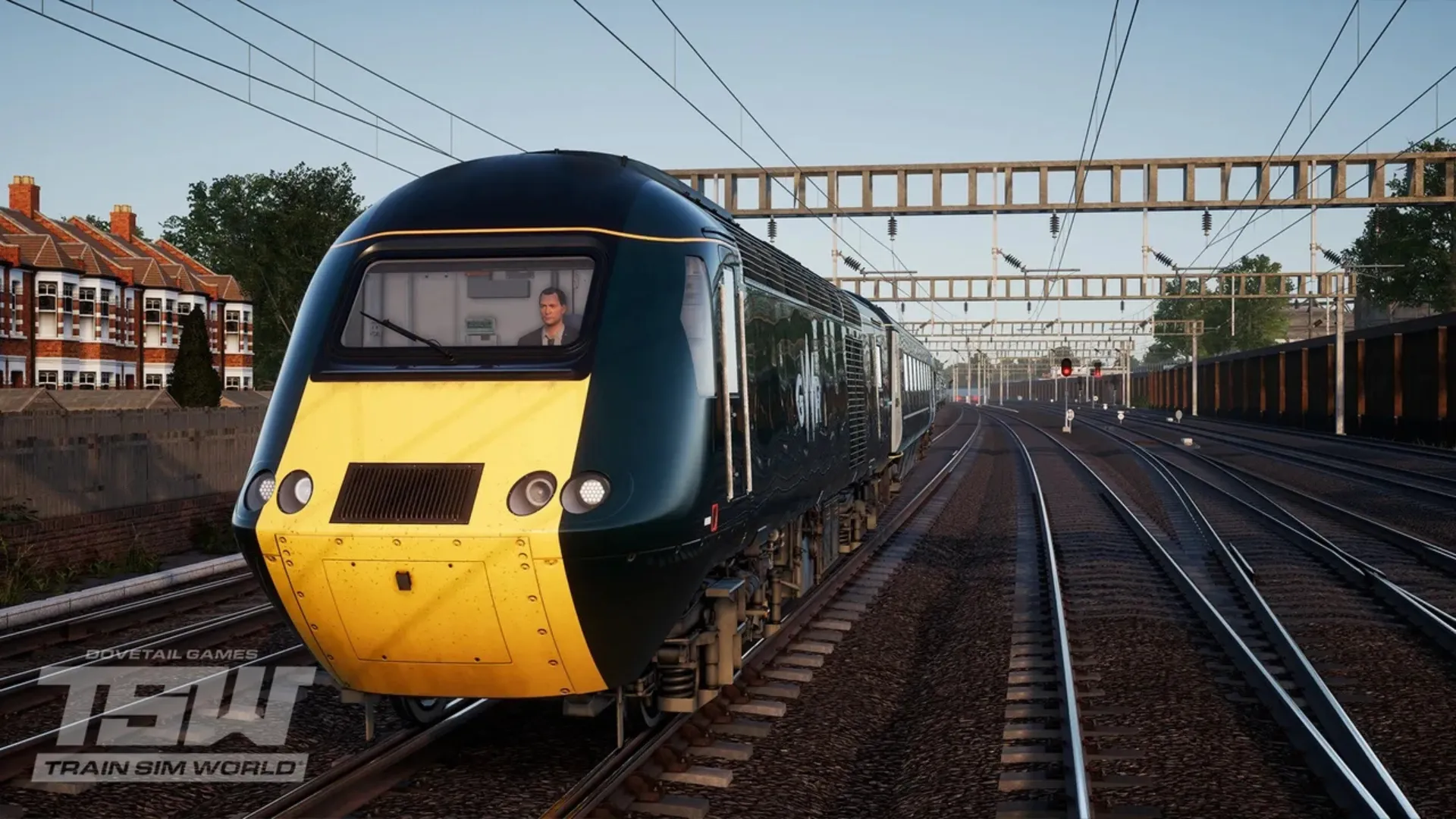 A green and yellow Great Western Railway high-speed train travels along electrified tracks past houses in Train Sim World.