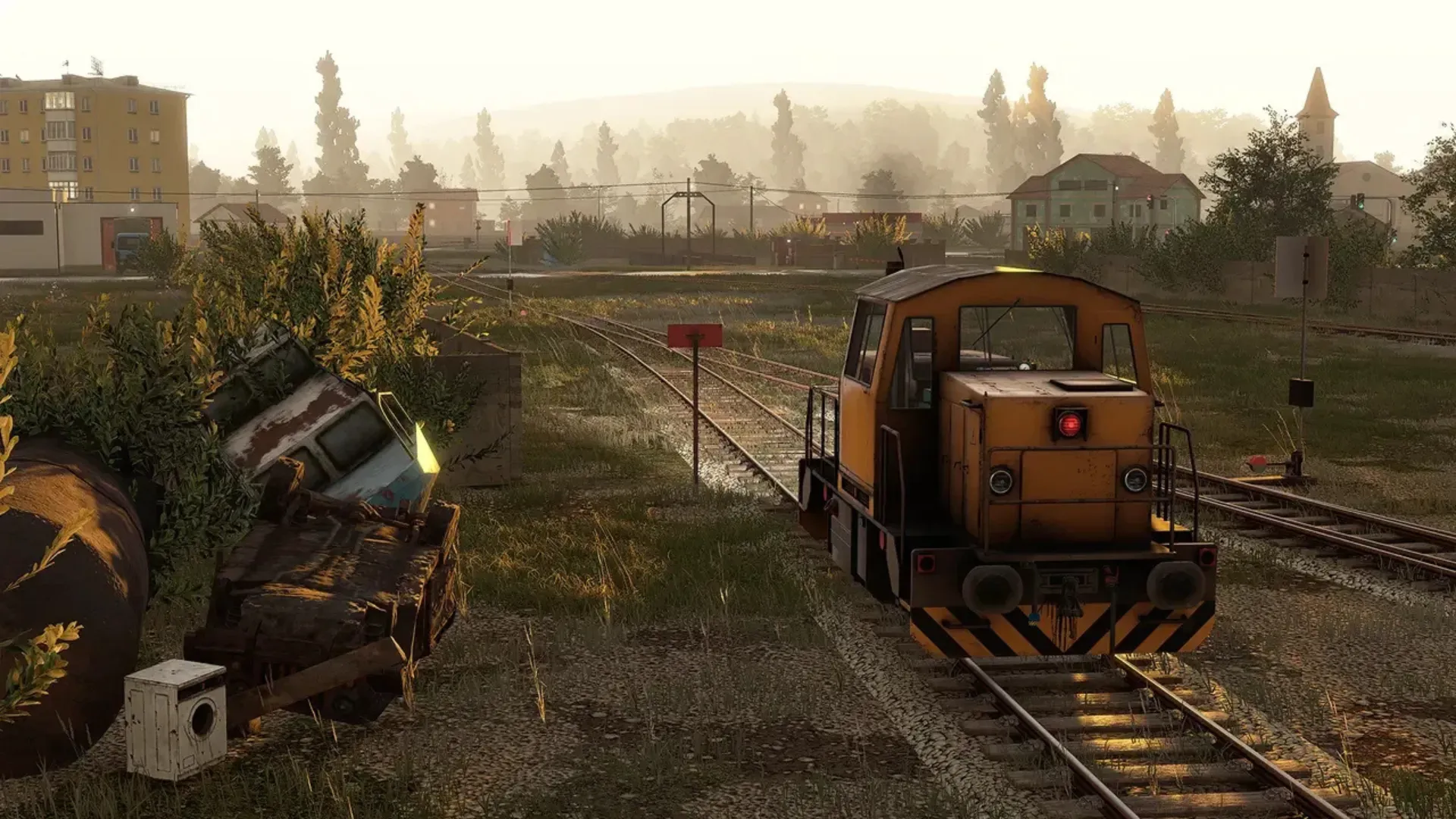 A weathered yellow shunting locomotive sits on rural tracks at dawn beside a derailed wagon in Derail Valley.