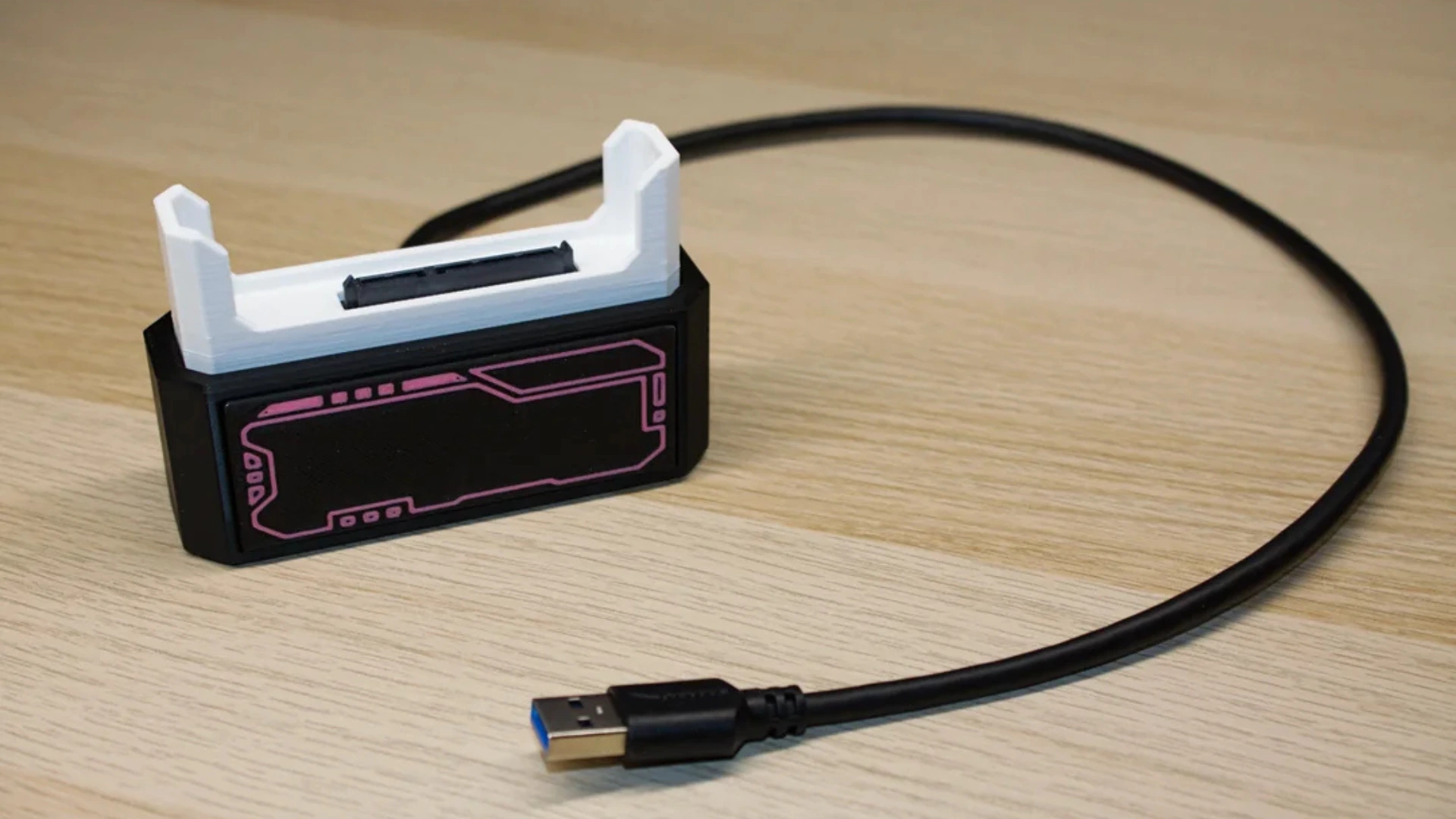 3D-printed SSD cartridge dock with a USB cable on a wooden desk
