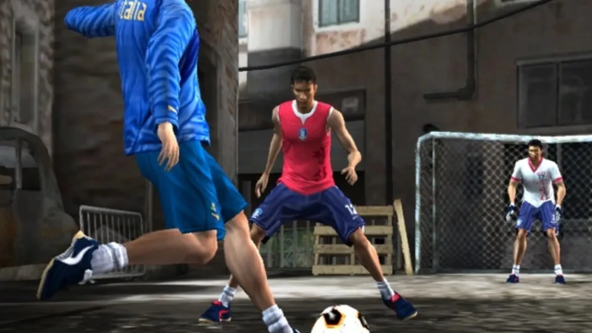 A player in an Italy tracksuit takes on defenders on a narrow street pitch with a keeper guarding a caged goal in FIFA Street 2.