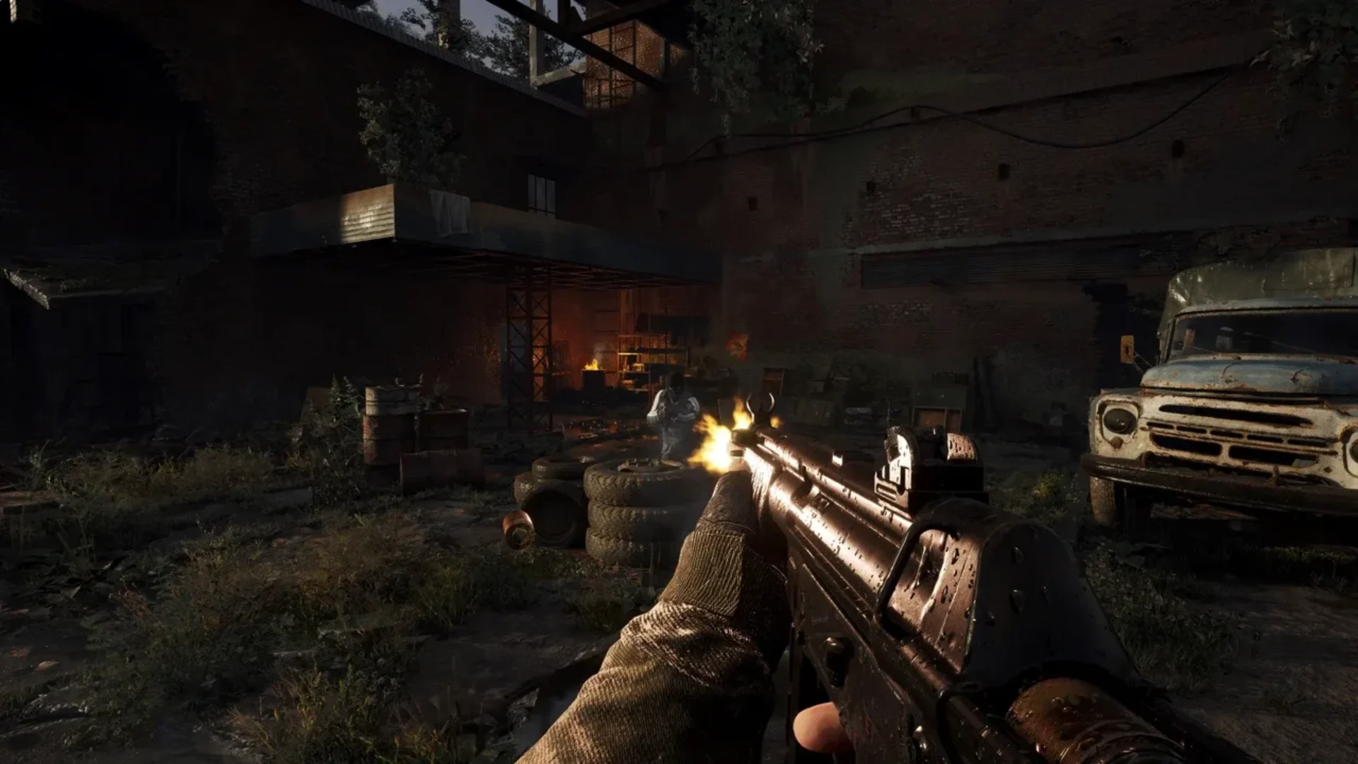 A STALKER 2 player fires an assault rifle at an enemy inside a dark warehouse.