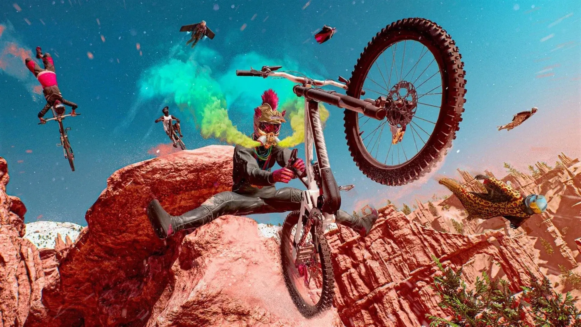 A mohawked rider pops a wheelie on a mountain bike over red rock as wingsuiters and bikers fill the sky in Riders Republic.