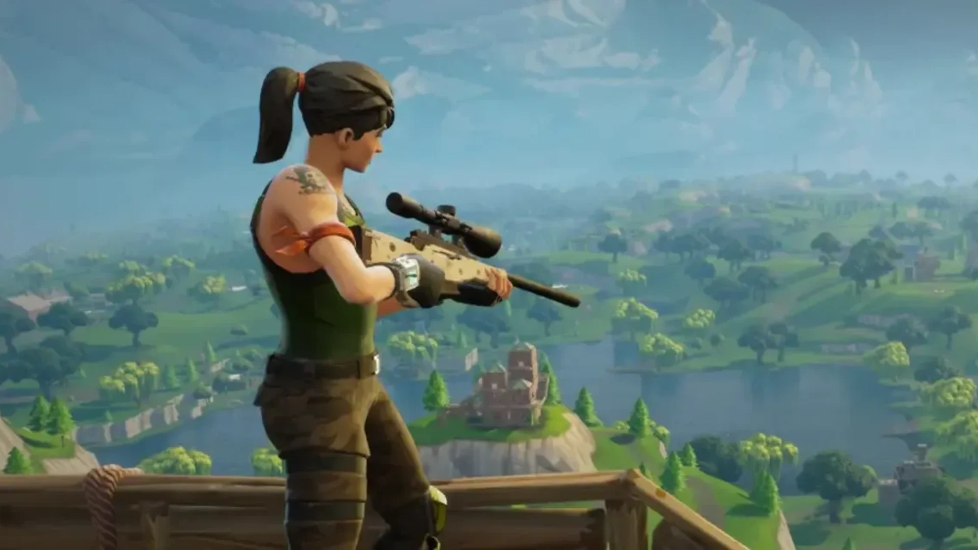 A Fortnite character holds a scoped rifle while overlooking the Battle Royale island from a wooden platform.