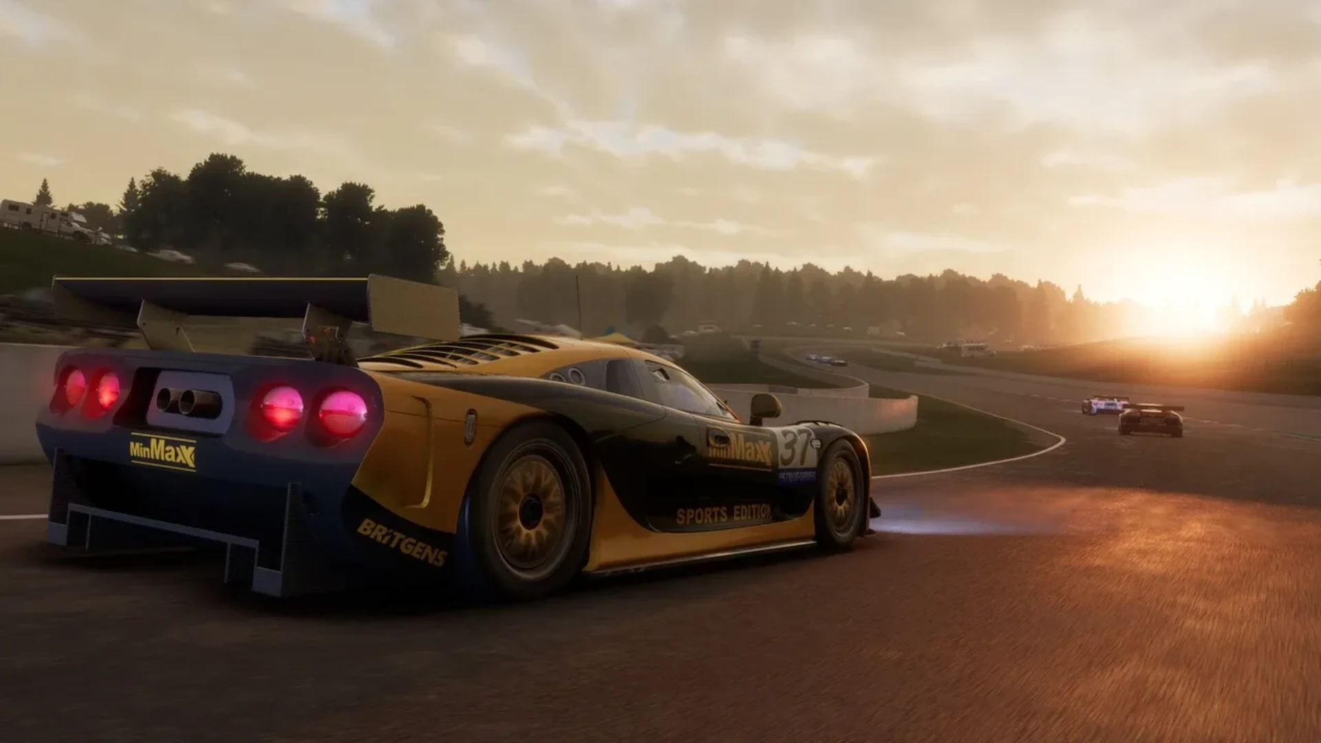 A yellow and black GT race car drives around a circuit during sunset.