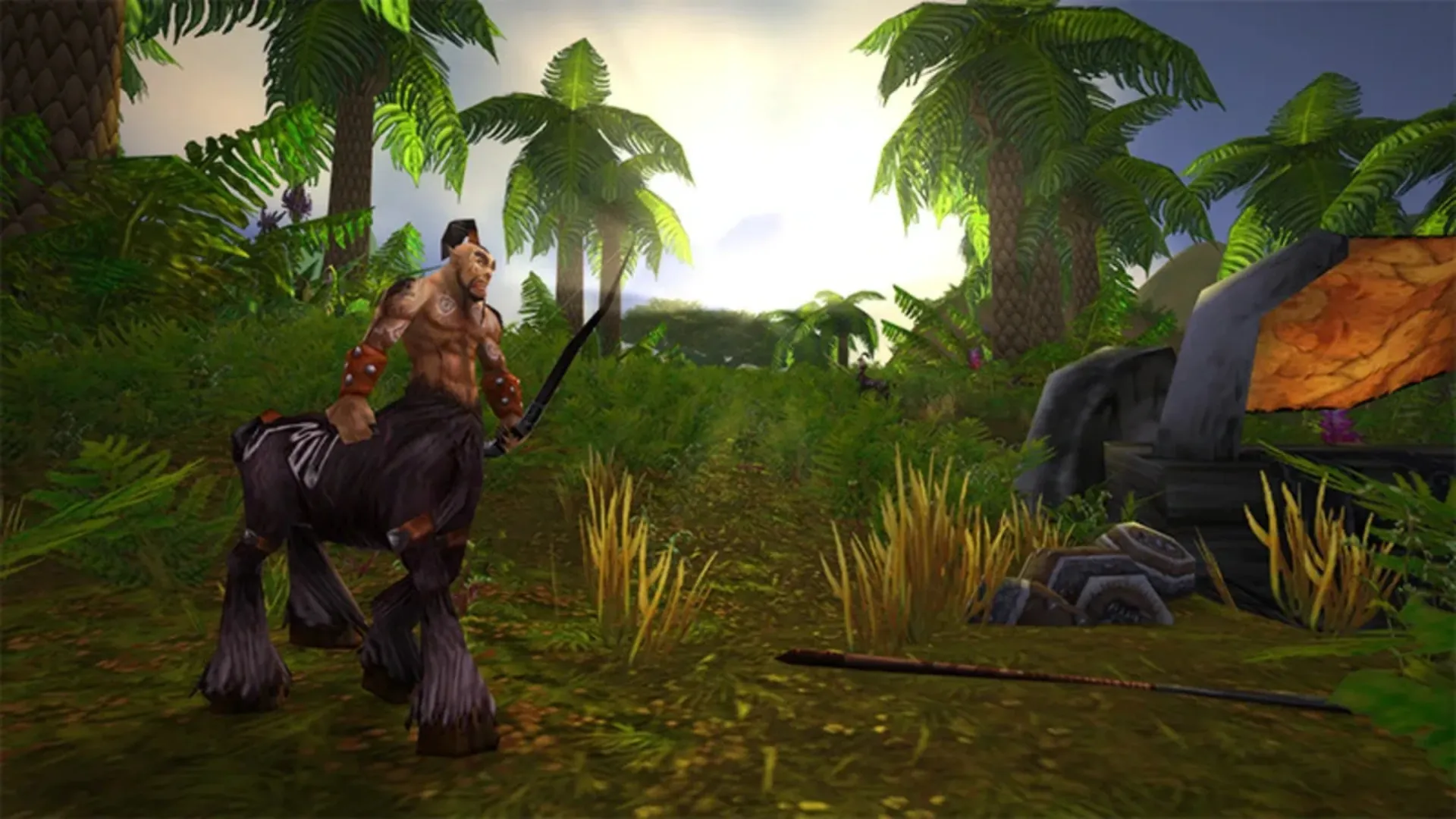 A centaur wielding a curved sword stands on a lush jungle path lined with palm trees and ferns in WoW Classic.