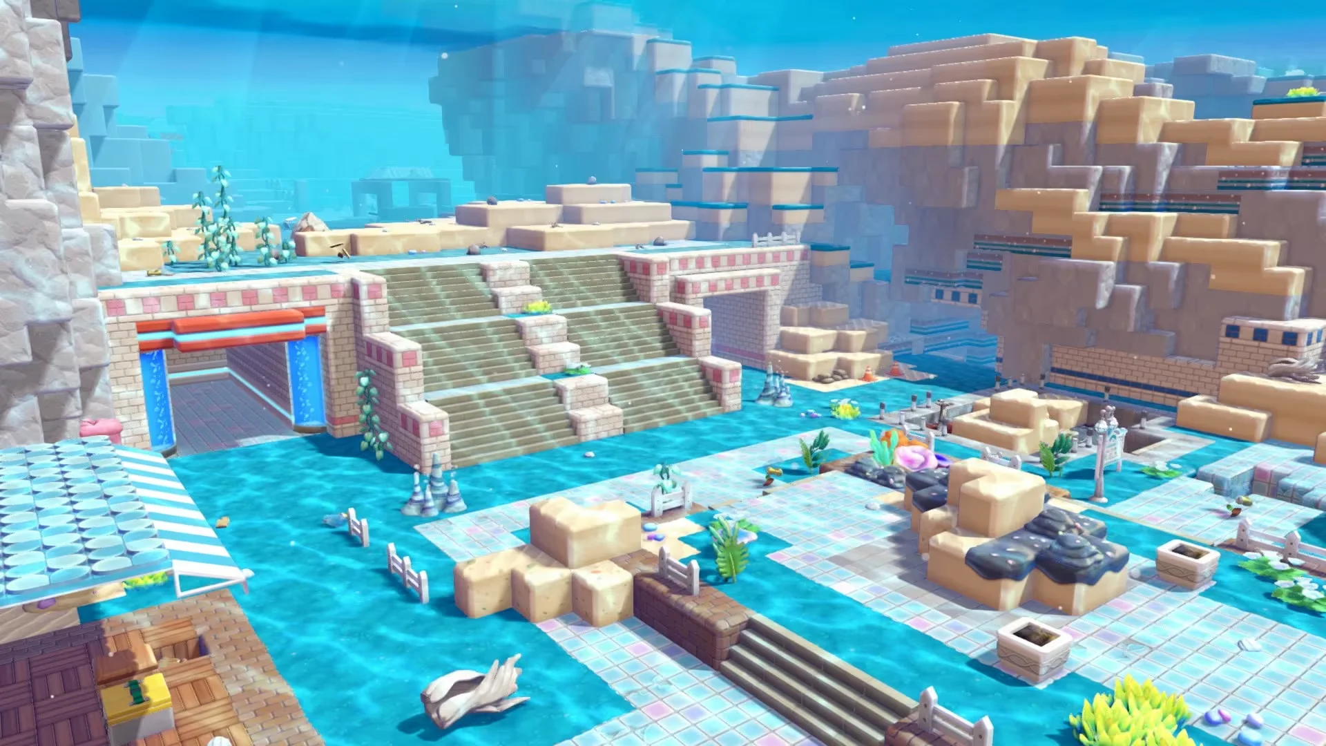 An underwater building area in Pokémon Pokopia features stone steps, tiled paths, plants, fences, and block structures.