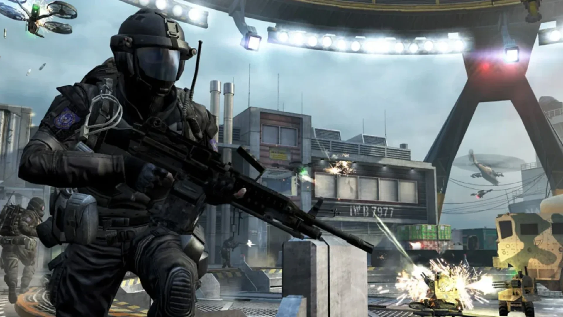 A heavily armed soldier runs through a Black Ops II multiplayer battle with drones and vehicles nearby.