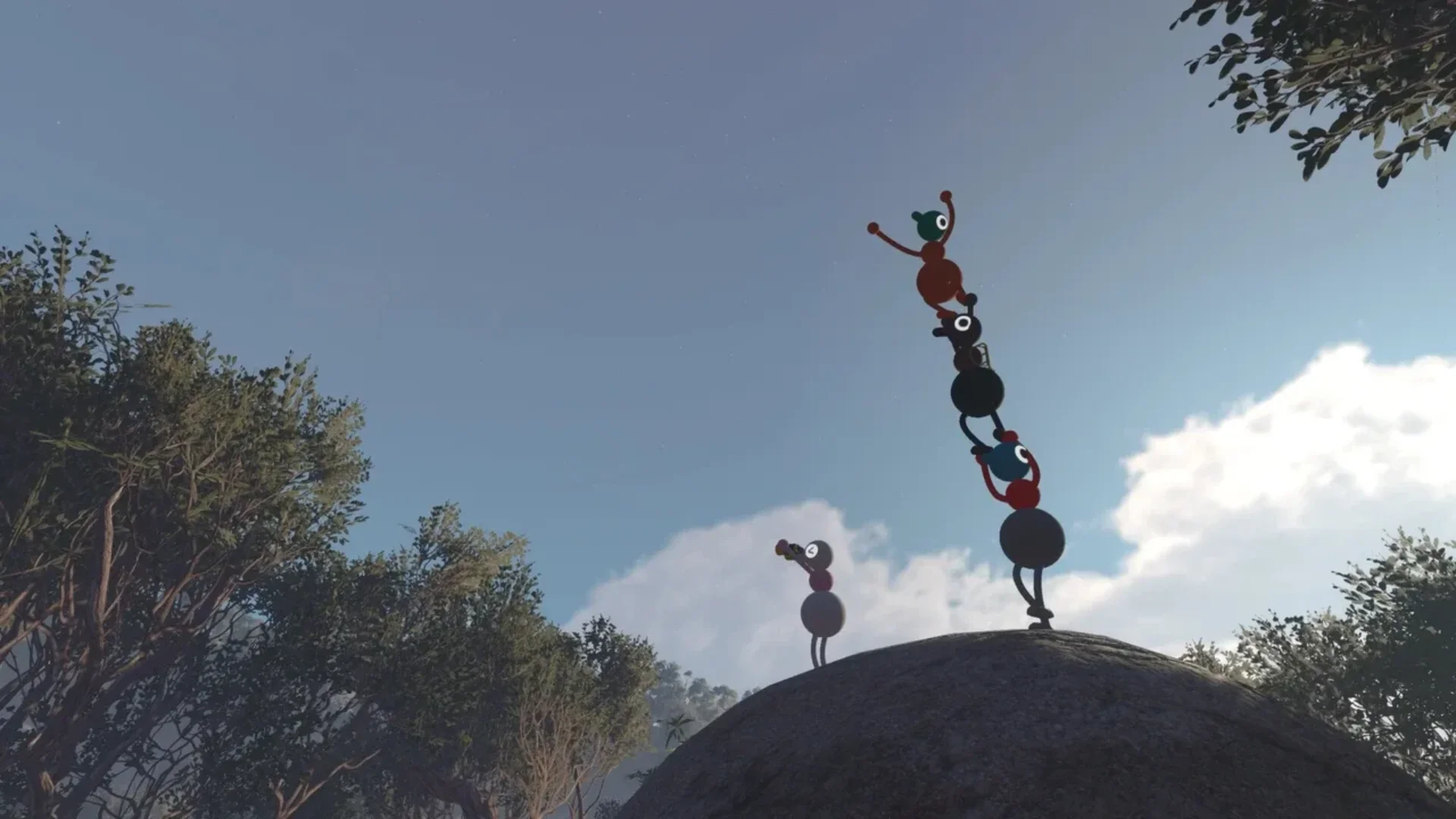 Several colourful Big Walk characters climb and balance across large rocks beside a beach and green hillside.