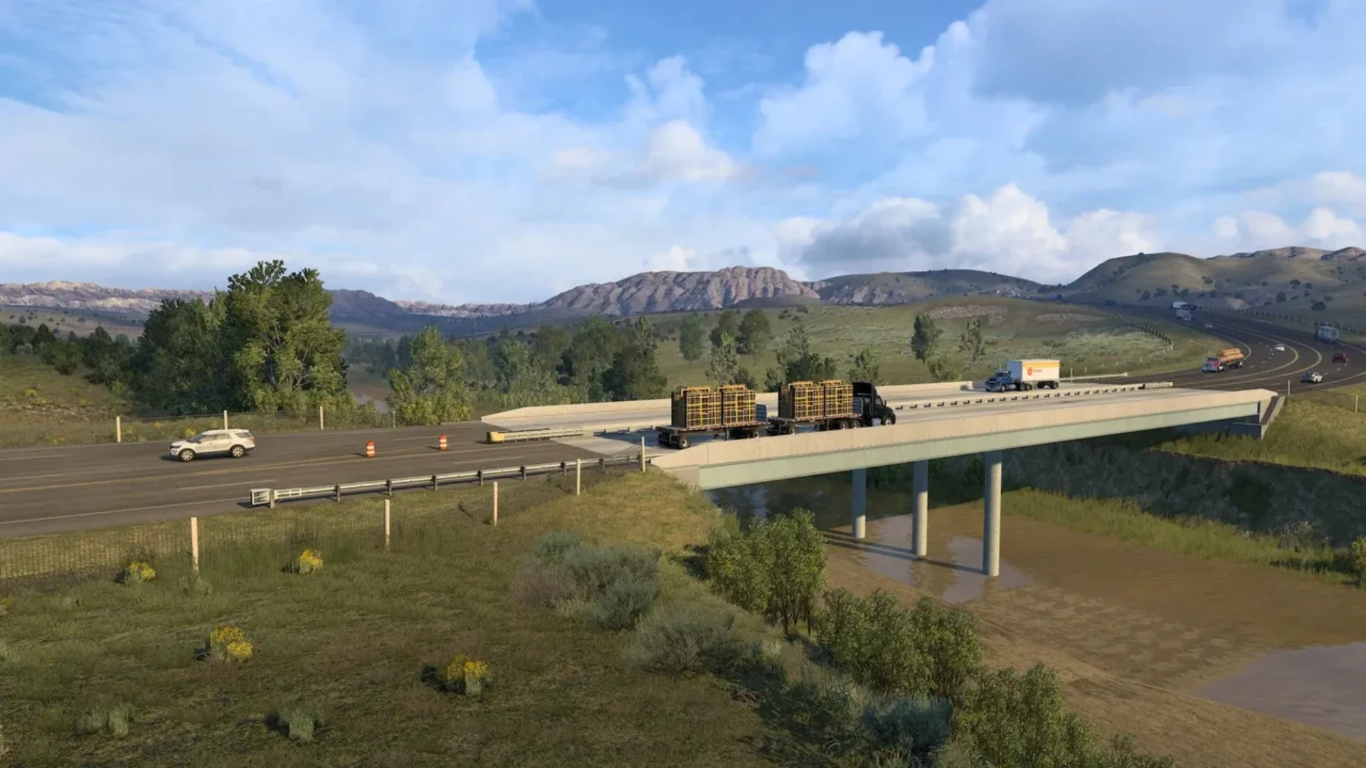 Trucks and cars travel across a highway bridge surrounded by grassland and distant North Dakota hills.