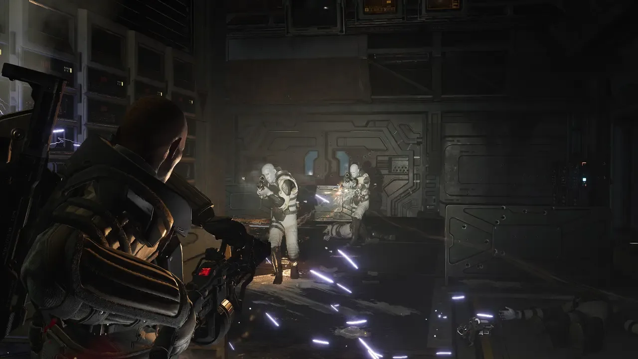 Marine firing at armored enemies during a firefight inside a dark spacecraft corridor in Aliens: Fireteam Elite 2.