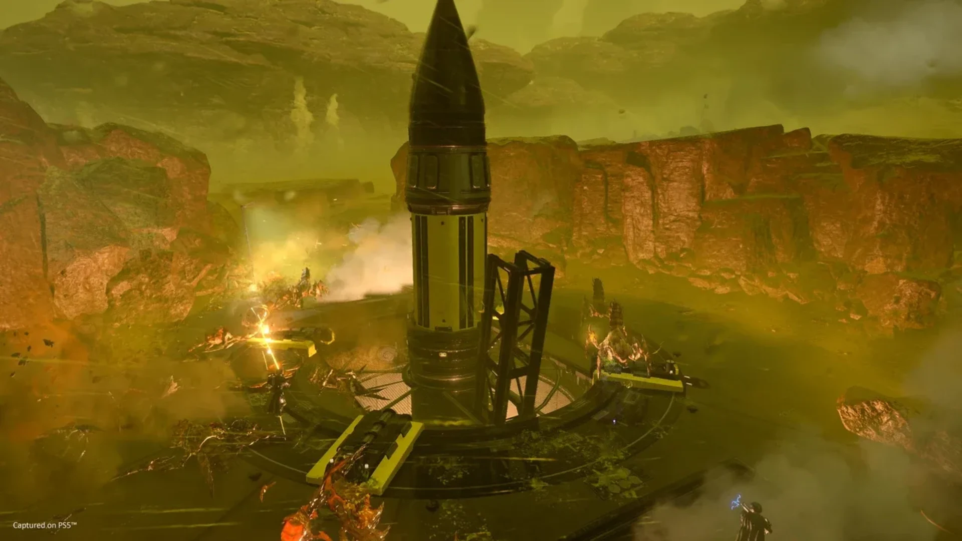 Helldivers 2 battlefield surrounds a large missile installation during combat with alien enemies.