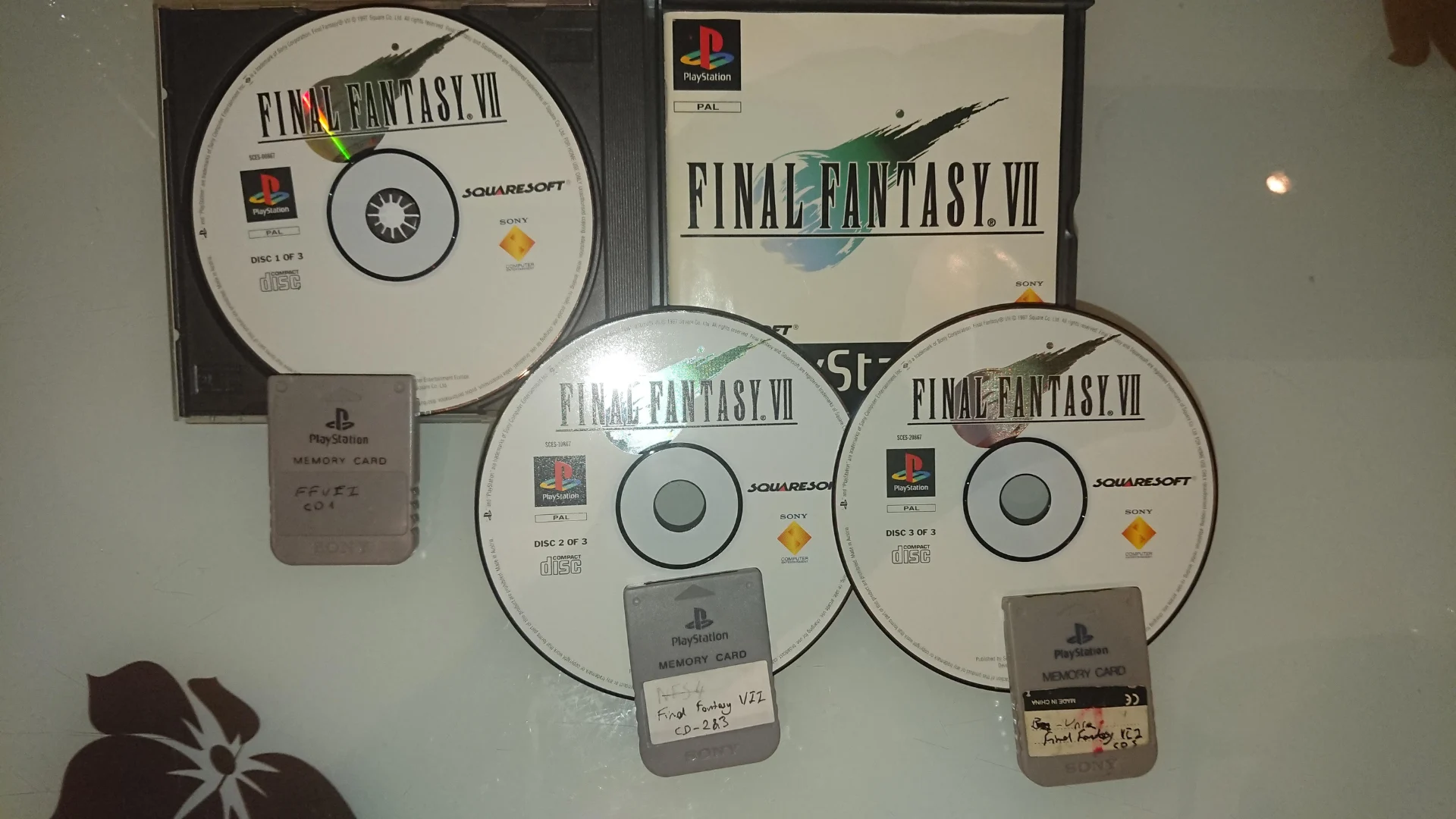 Final Fantasy 7 PlayStation discs, game case and three PlayStation memory cards arranged together.