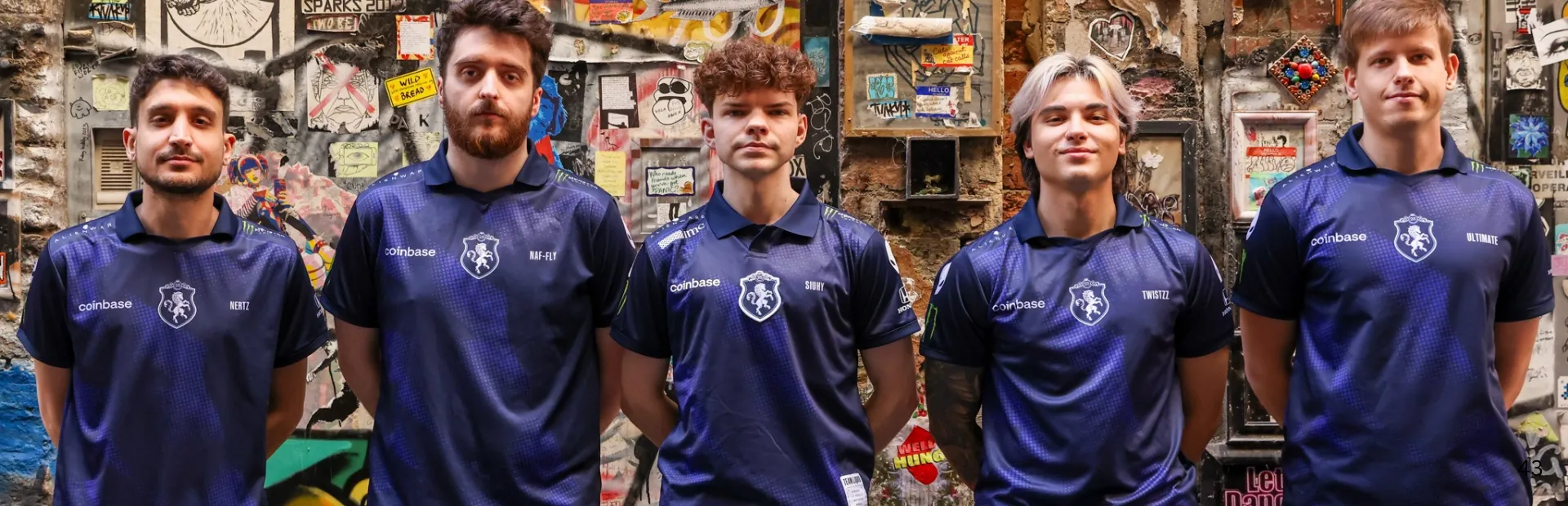 Team Liquid Counter-Strike players in blue jerseys stand in a row before a graffiti-covered wall.
