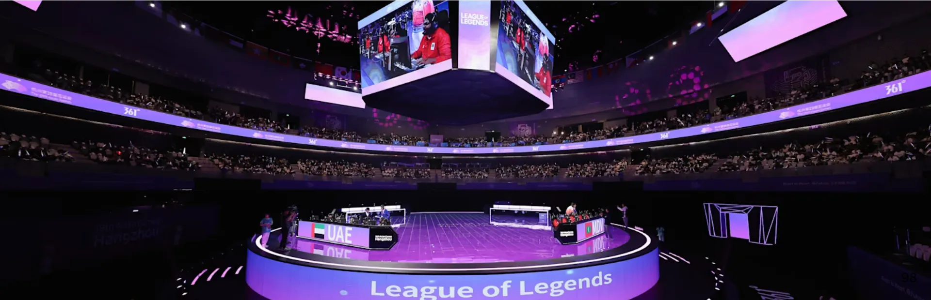 League of Legends teams compete on a circular stage inside a packed Asian Games esports arena