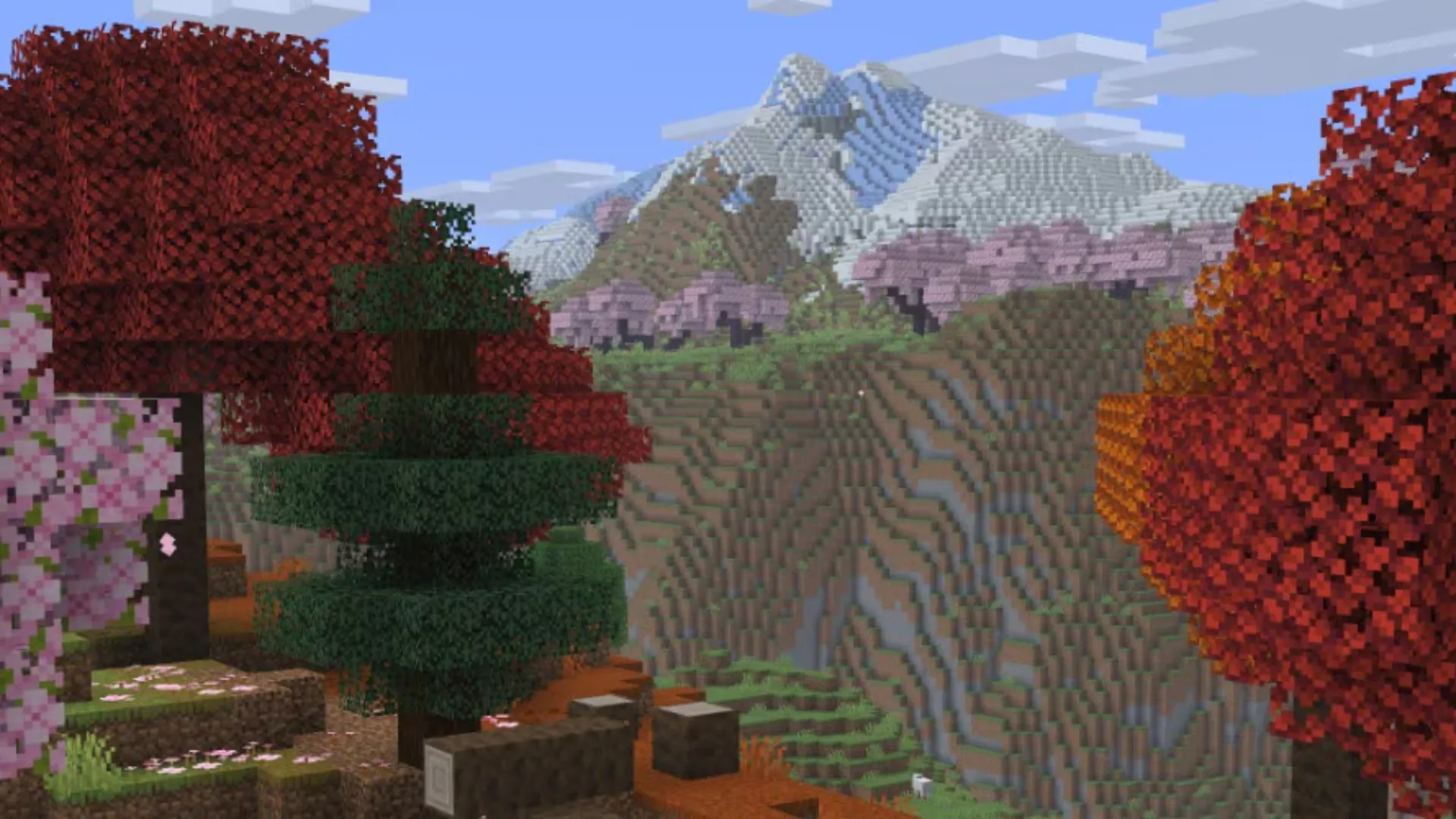 Autumn trees and pink blossoms overlook steep mountains in Minecraft Java Edition
