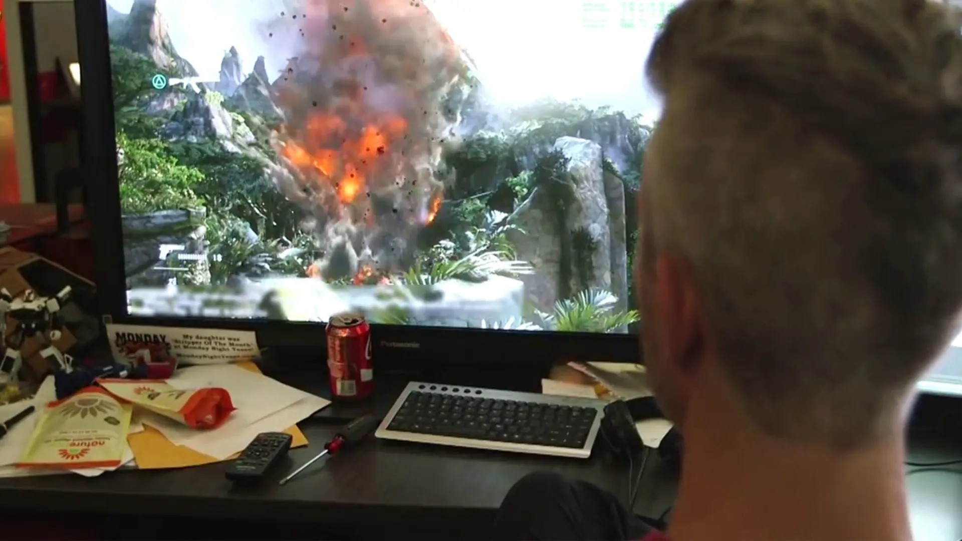 A developer watches a fiery jungle explosion in an Uncharted game on a large screen at the Naughty Dog studio.