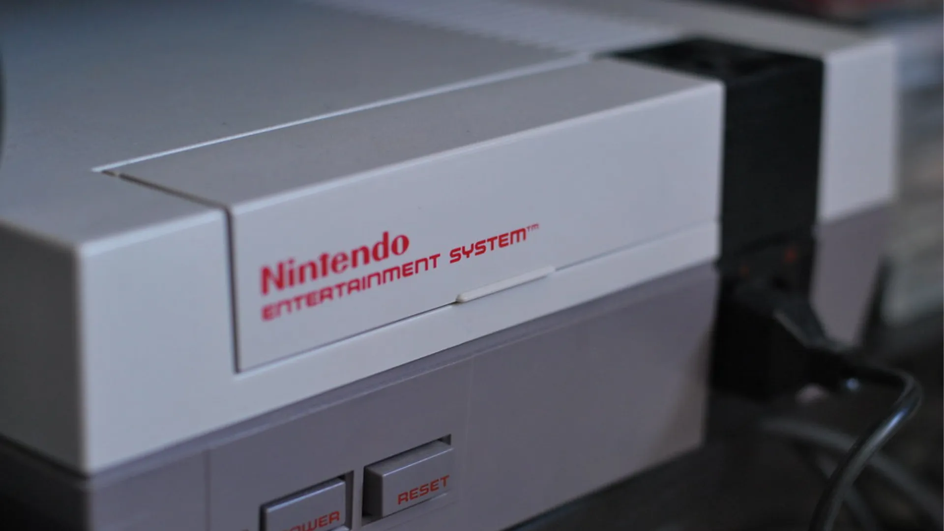 Close-up of a grey Nintendo Entertainment System console showing the red NES logo and the power and reset buttons.