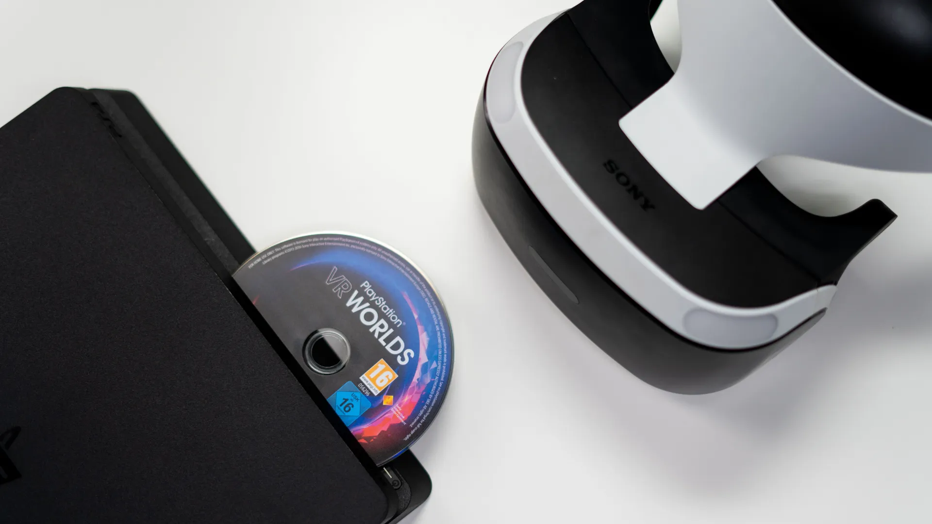 A PlayStation VR Worlds game disc sits beside a PlayStation VR headset and console.