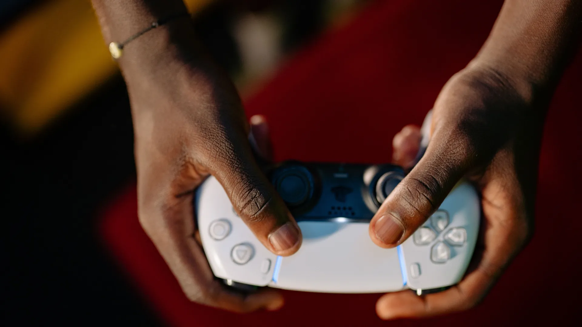 Close-up of a player holding a white PlayStation DualSense controller with both hands.