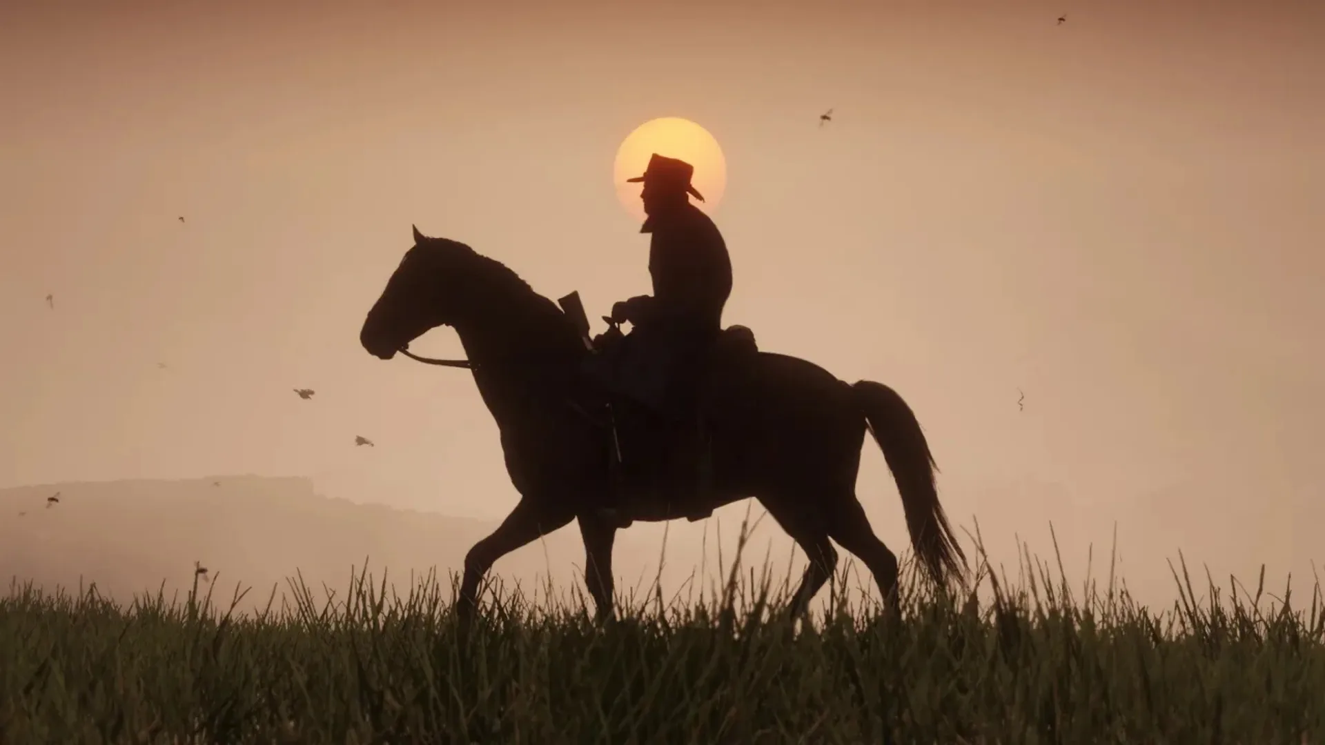 A rider on horseback crosses a field in silhouette against the setting sun in Red Dead Redemption 2.