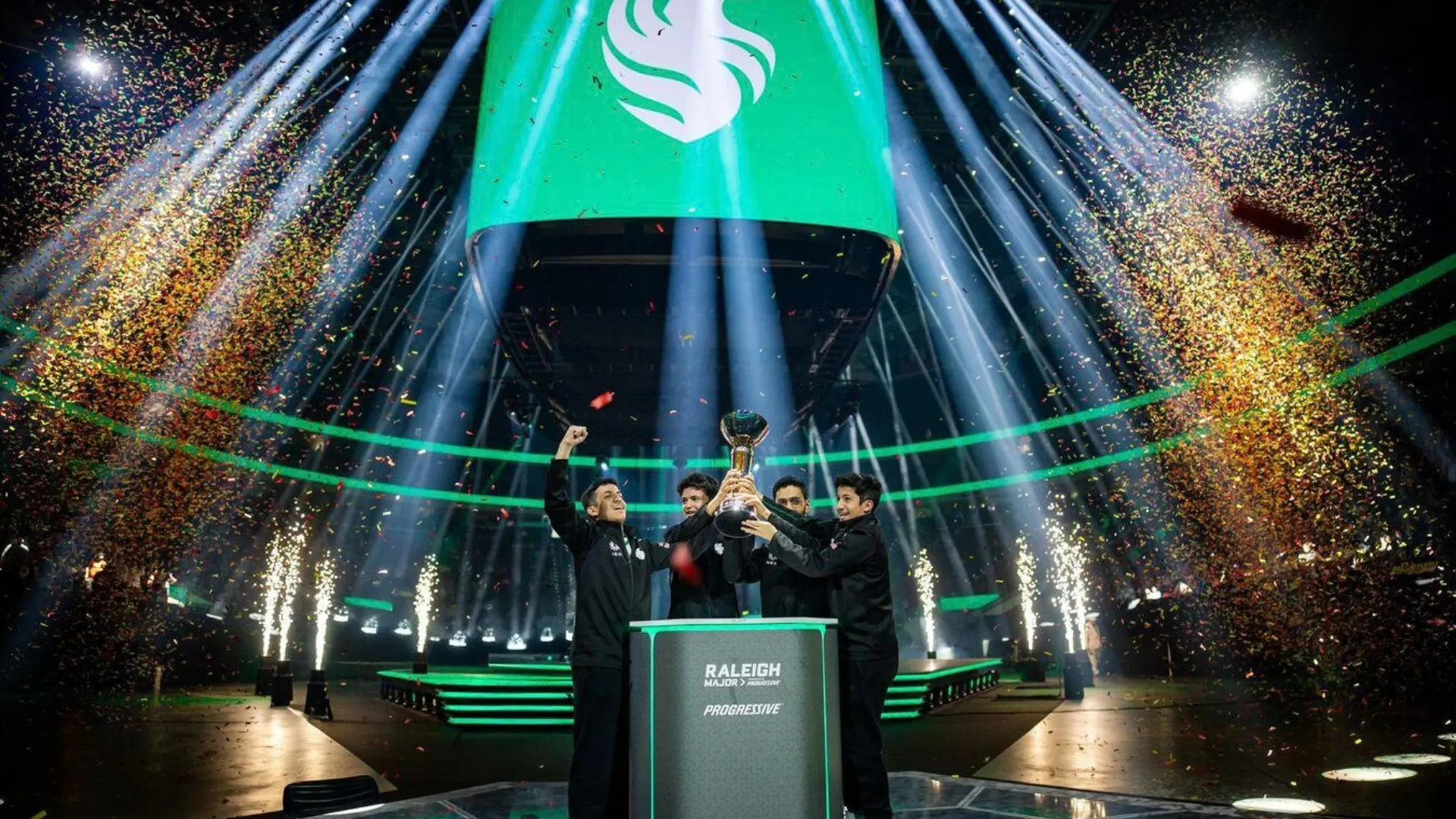 Team Falcons players lift the Raleigh Major trophy as confetti falls across the stage