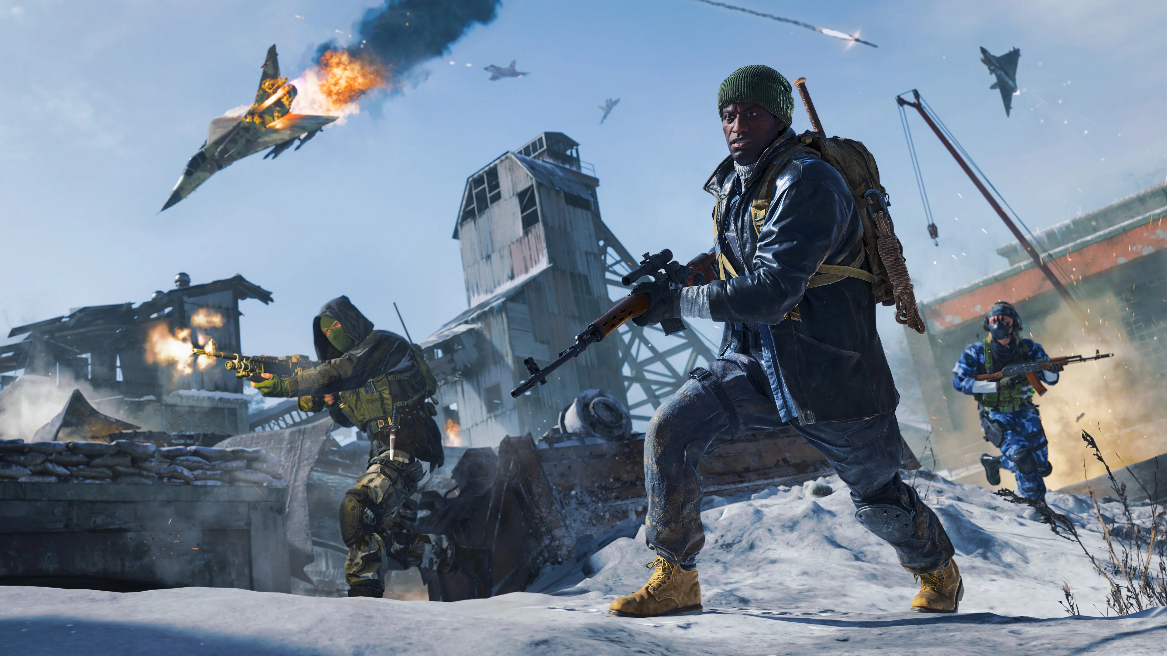 Three Call of Duty soldiers carry rifles across a snowy industrial battlefield while a damaged fighter jet burns overhead.