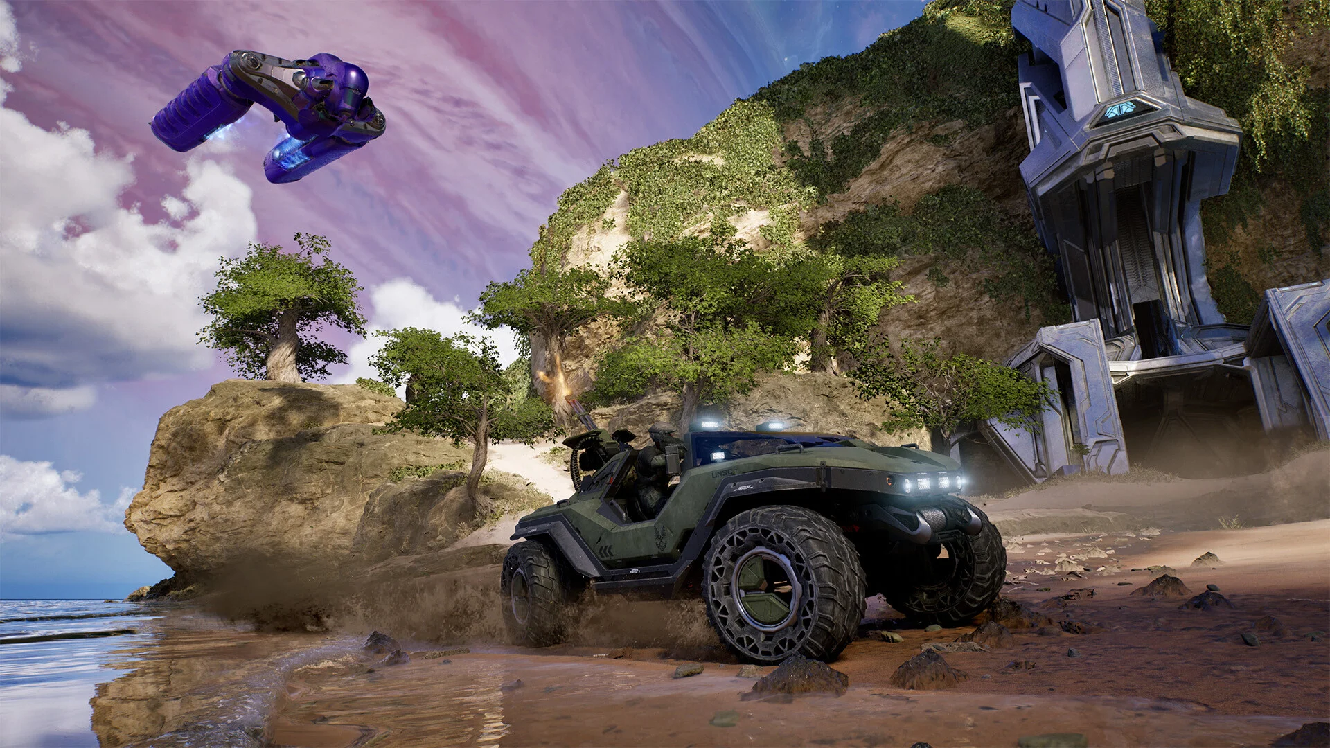 A Halo Warthog drives along a coastal battlefield while a purple Banshee flies overhead near a Forerunner structure.