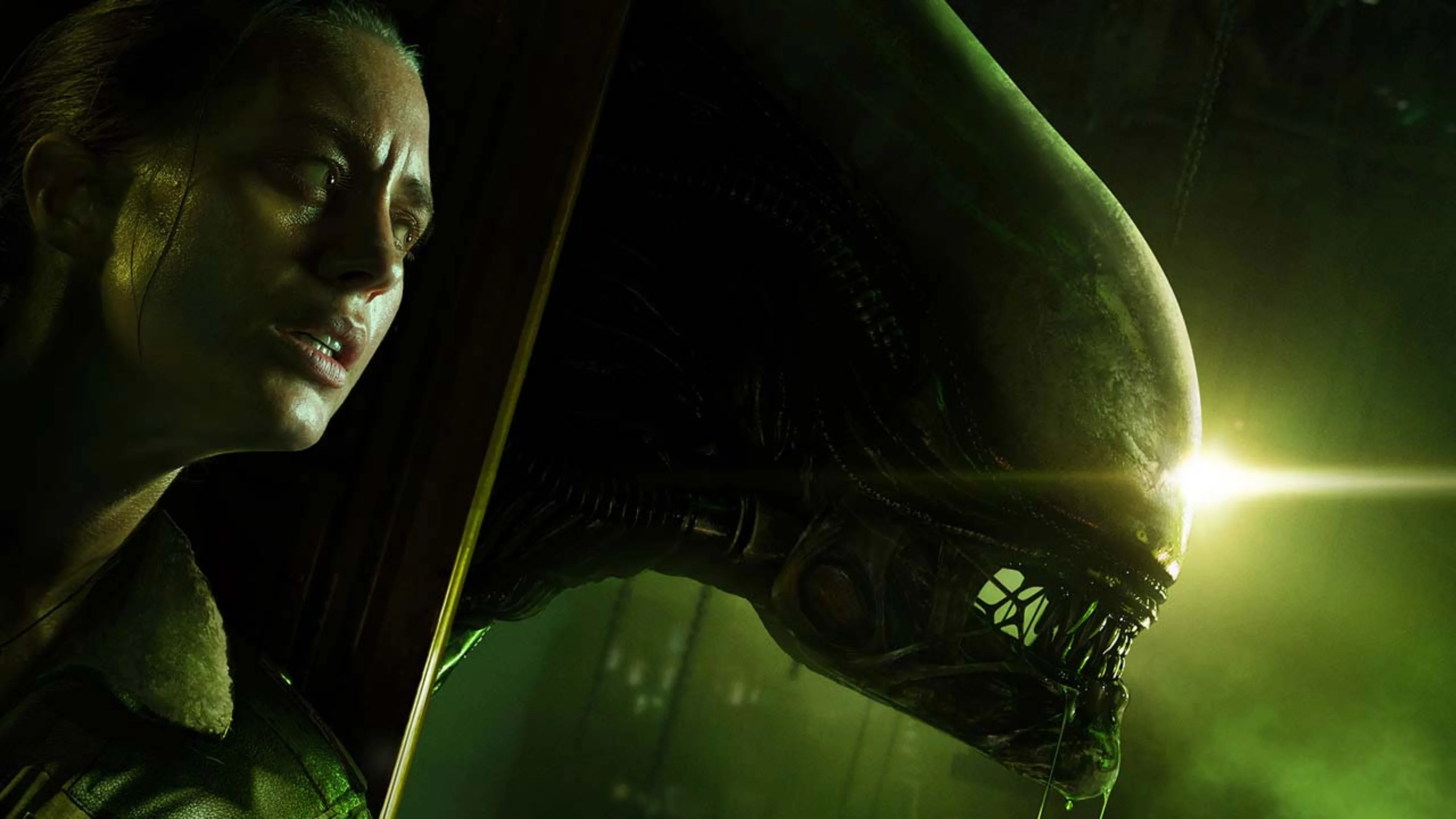 A woman stands beside a Xenomorph with exposed teeth and a large elongated head, illuminated by eerie green light.