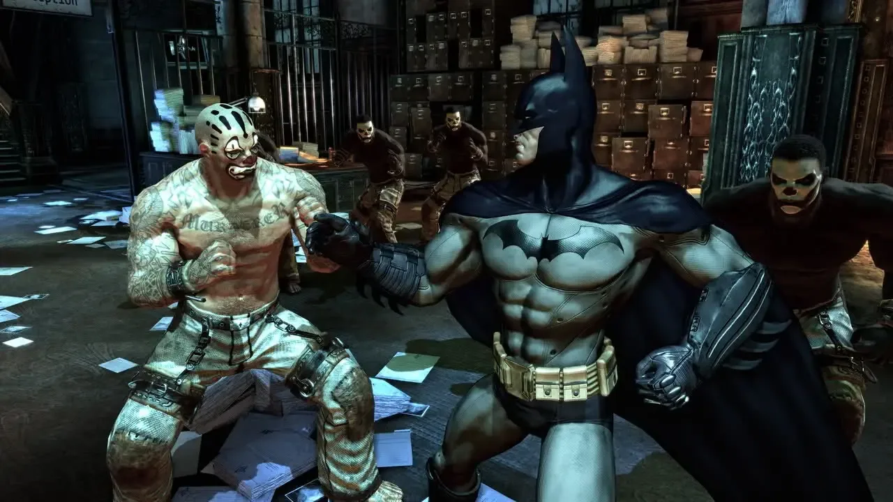 Batman fights a tattooed inmate while surrounded by other enemies in Arkham Asylum.