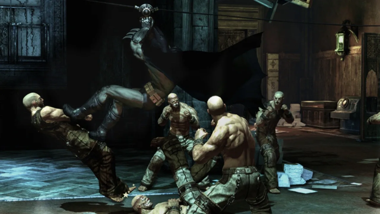 Batman performs a flying kick against a group of inmates inside Arkham Asylum.