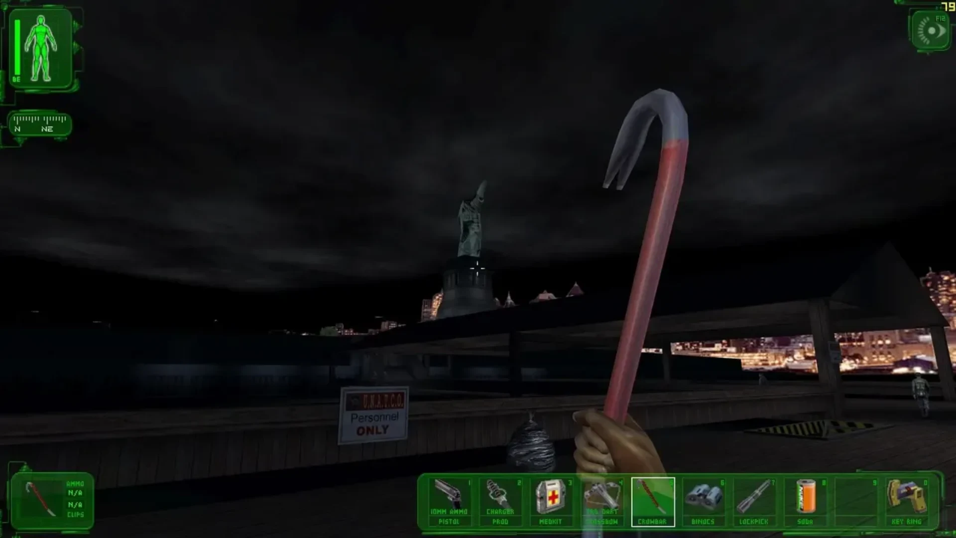 First-person Deus Ex gameplay showing the player holding a crowbar near the Statue of Liberty at night.
