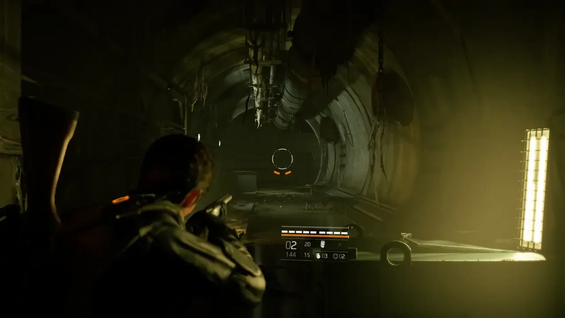 The Division 2 agent aims a weapon while exploring a dimly lit underground corridor.