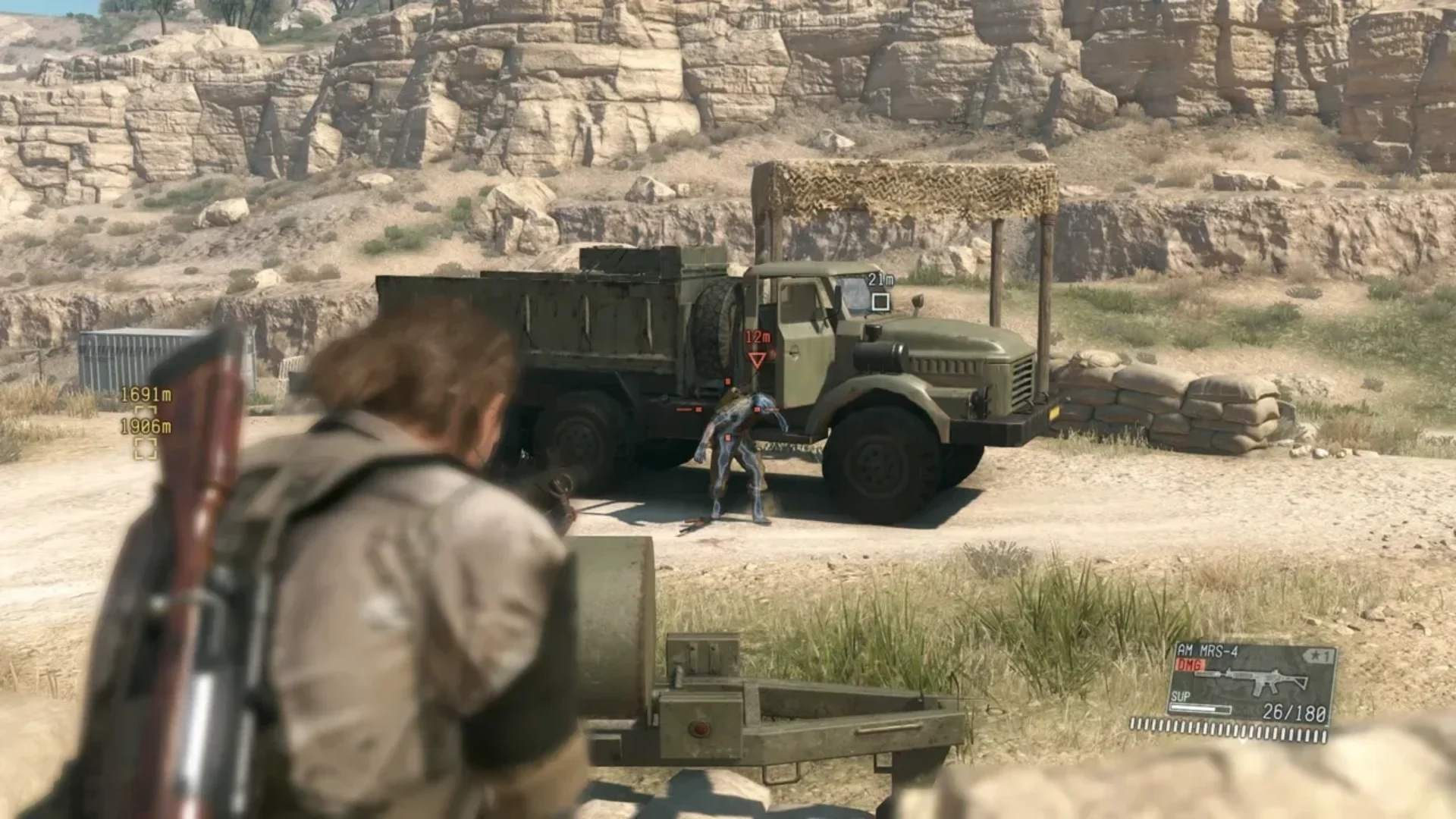 Venom Snake aims at an enemy soldier beside a military truck in Metal Gear Solid V.