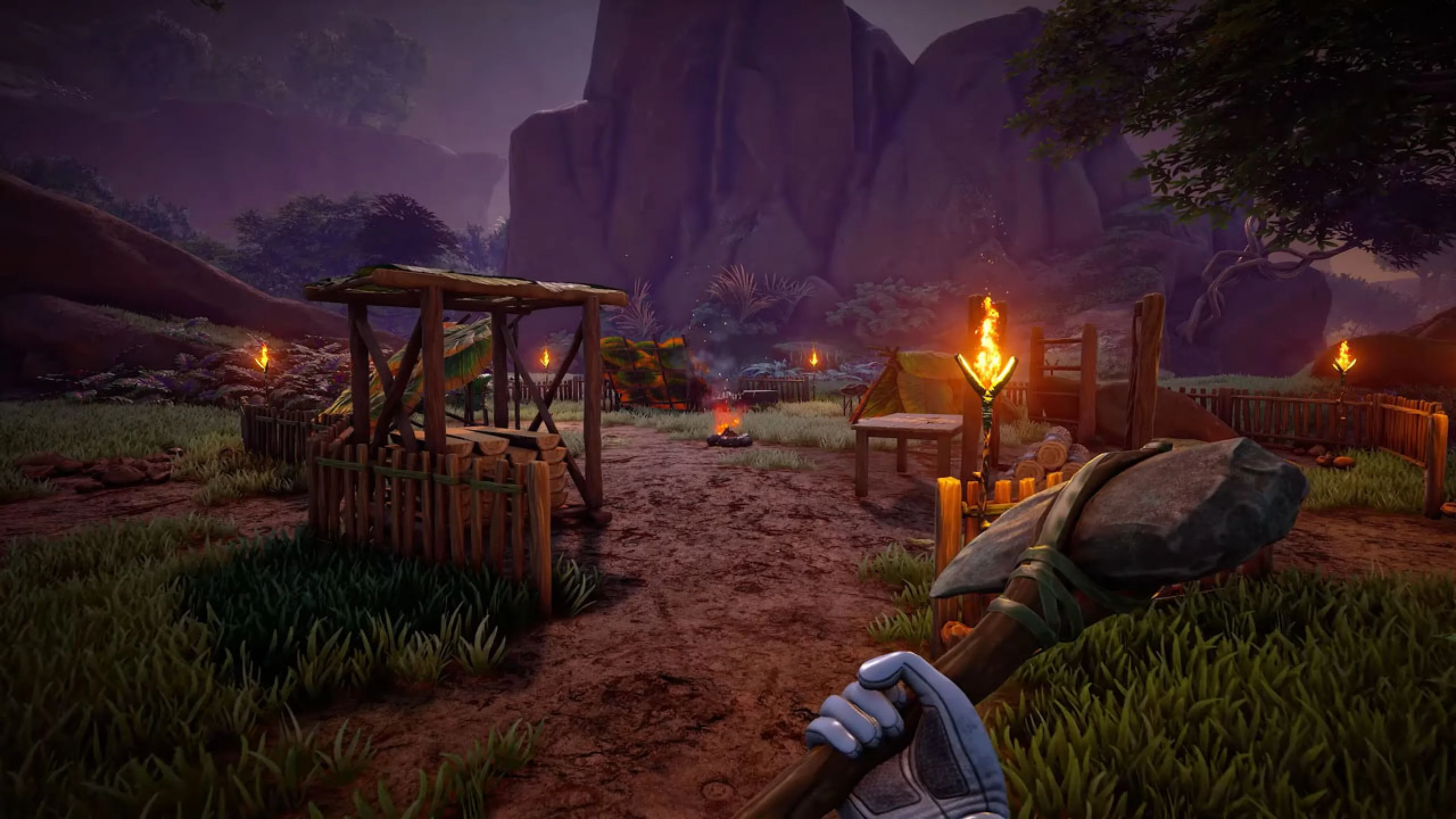 First-person Blind Descent gameplay shows a stone axe held near a survival camp with wooden fences, tents, torches and a campfire.