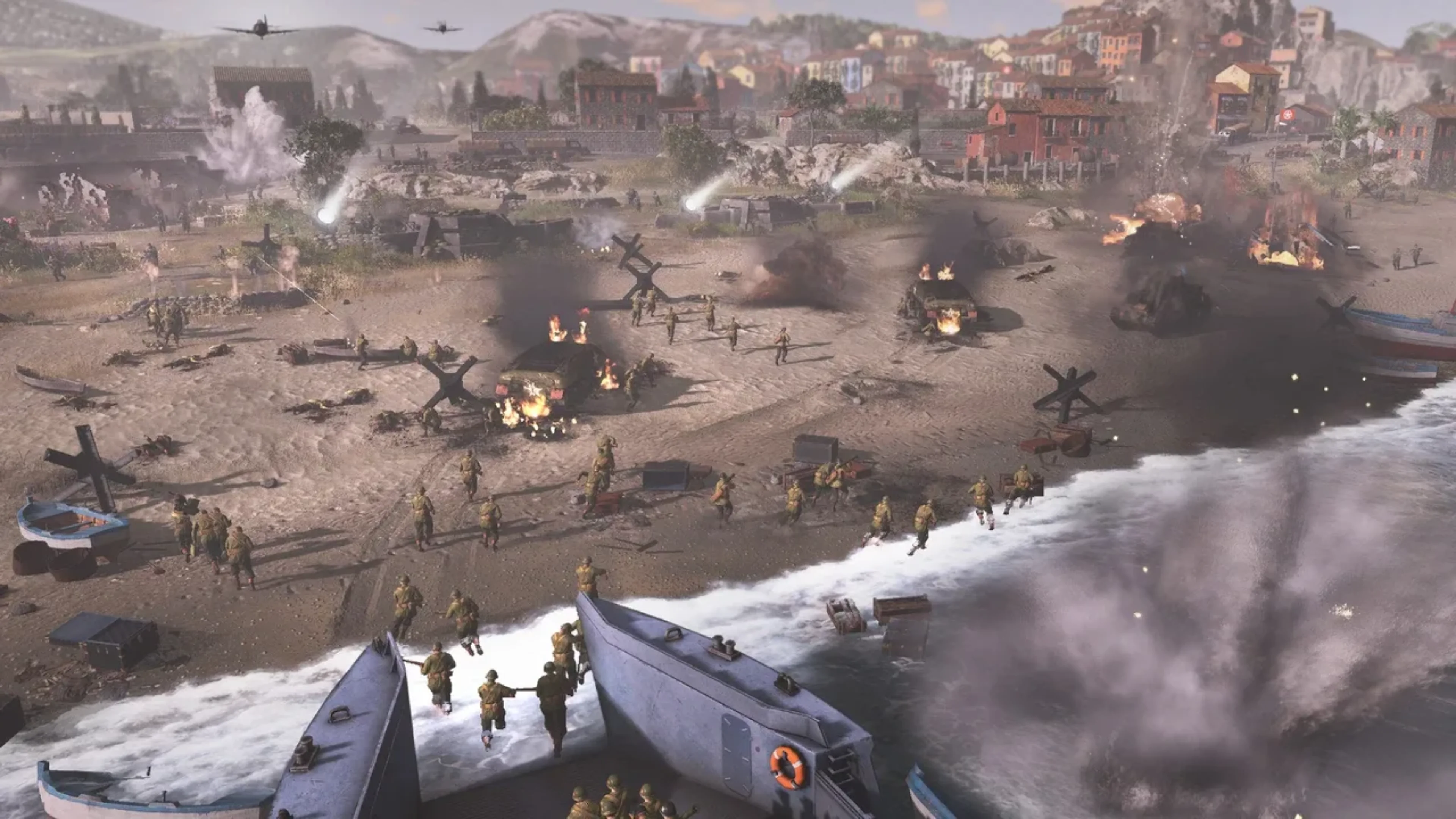 American soldiers storm a North African beach from landing craft amid burning vehicles, explosions, aircraft, and defensive barriers in Company of Heroes 3: Operation Torch.