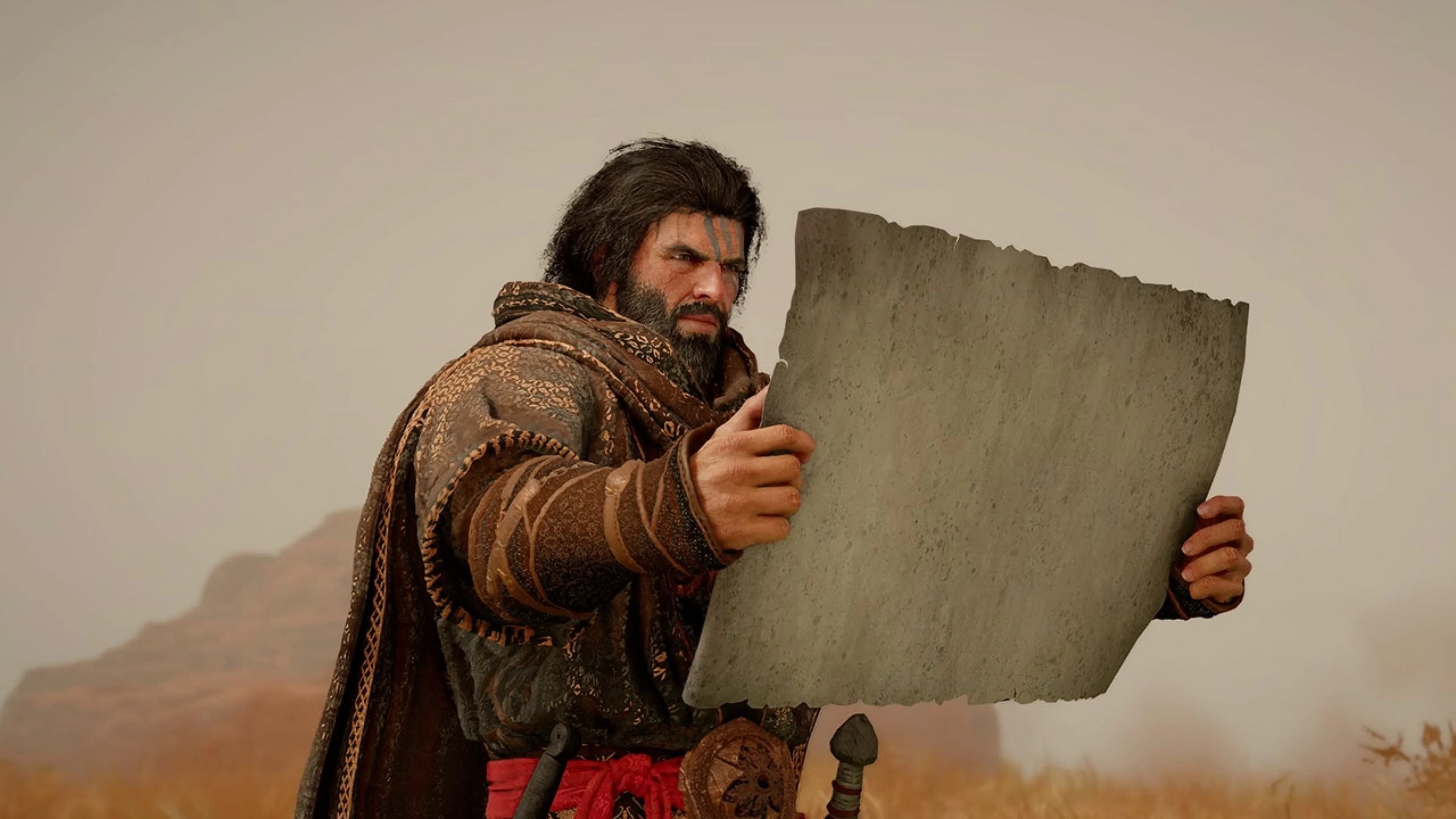 A bearded adventurer wearing brown armor and a cloak studies a large map while standing in a sandy landscape in Crimson Desert.