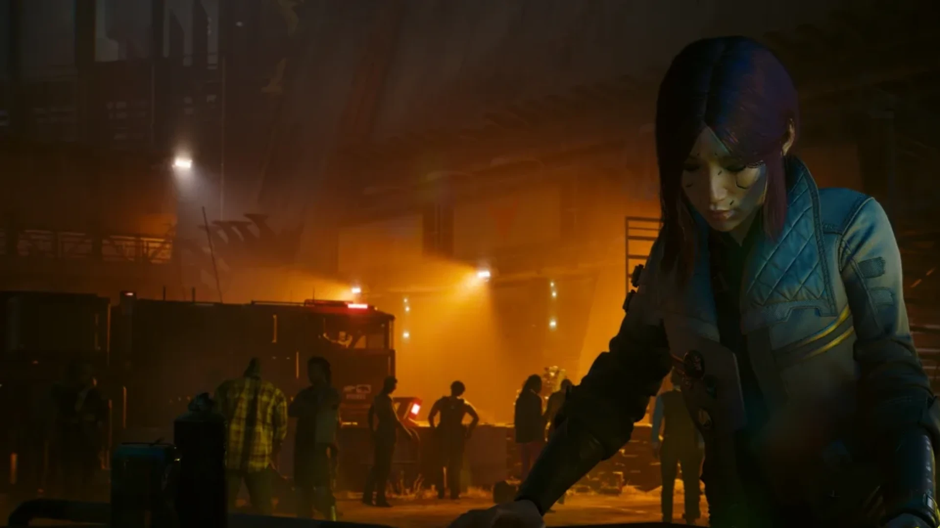 A dark-haired character stands in the foreground of a dimly lit urban area illuminated by orange lights in Cyberpunk 2077.