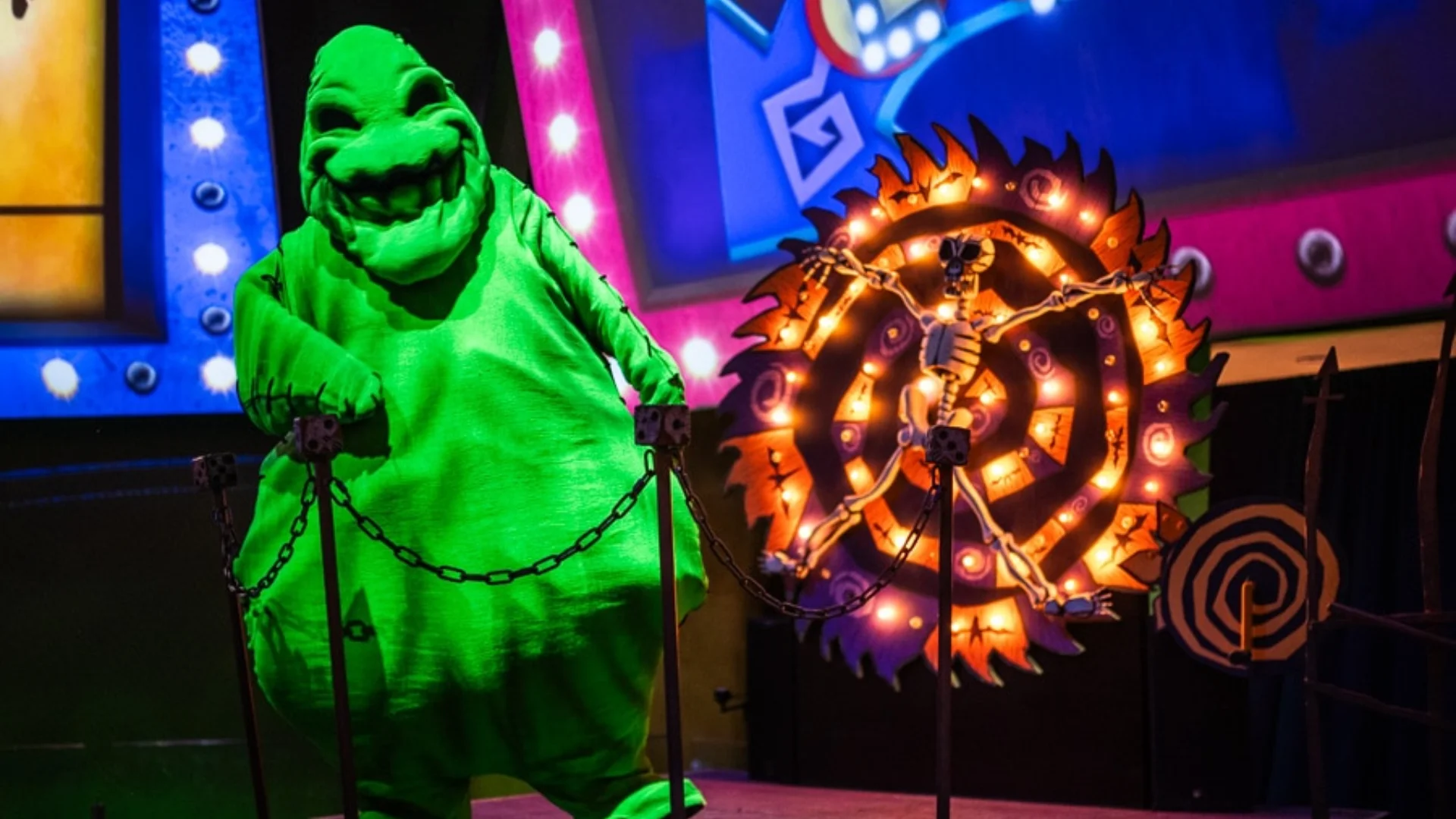 Oogie Boogie stands beside a glowing Halloween wheel in a colorful Disney Dreamlight Valley display.