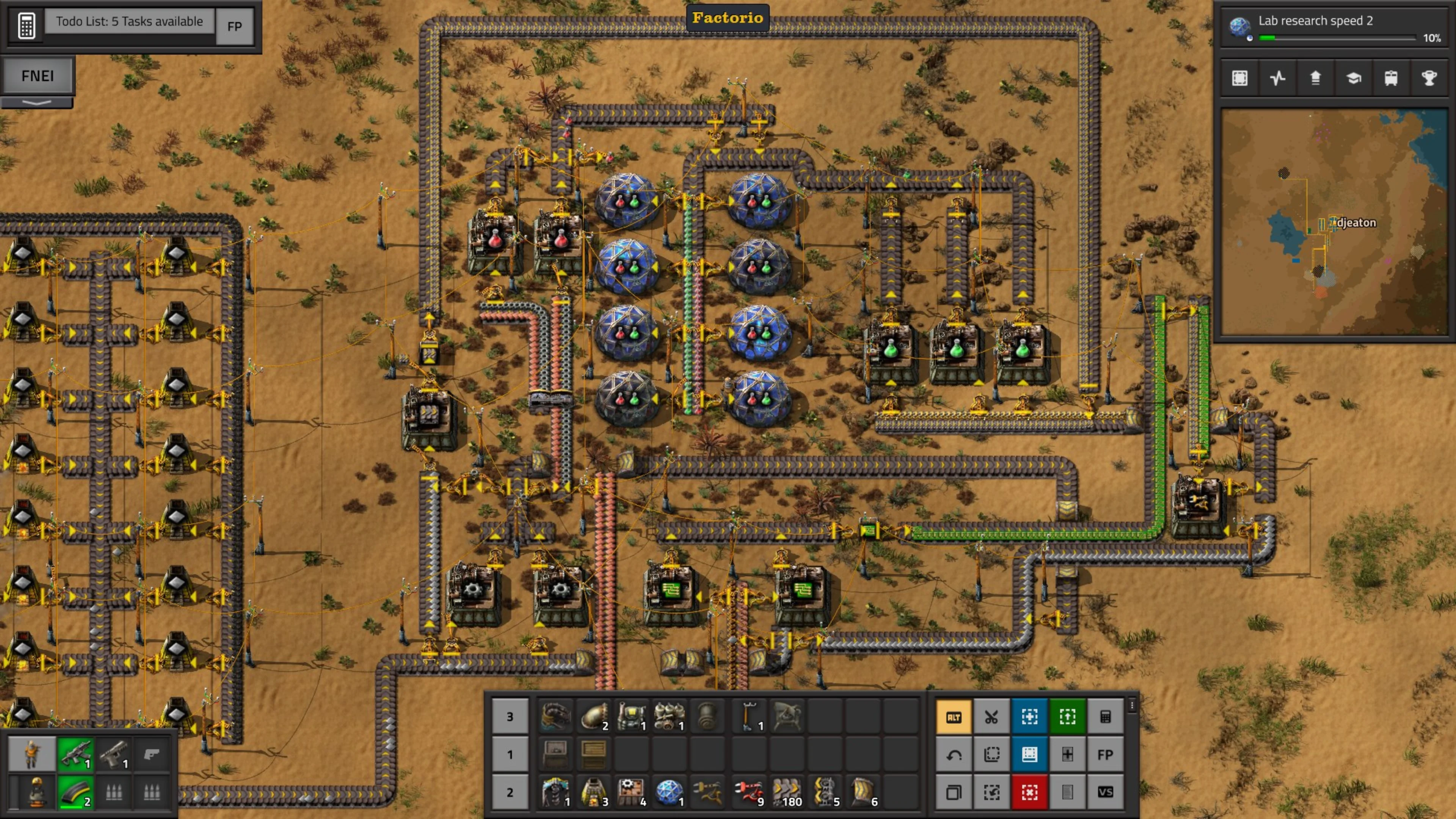 Factorio factory with research labs, conveyor belts, inserters, circuit wiring and production machines on a desert map.