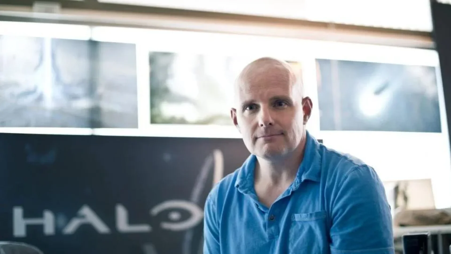 A former Halo creative director sits in a studio with illuminated Halo branding visible behind him.