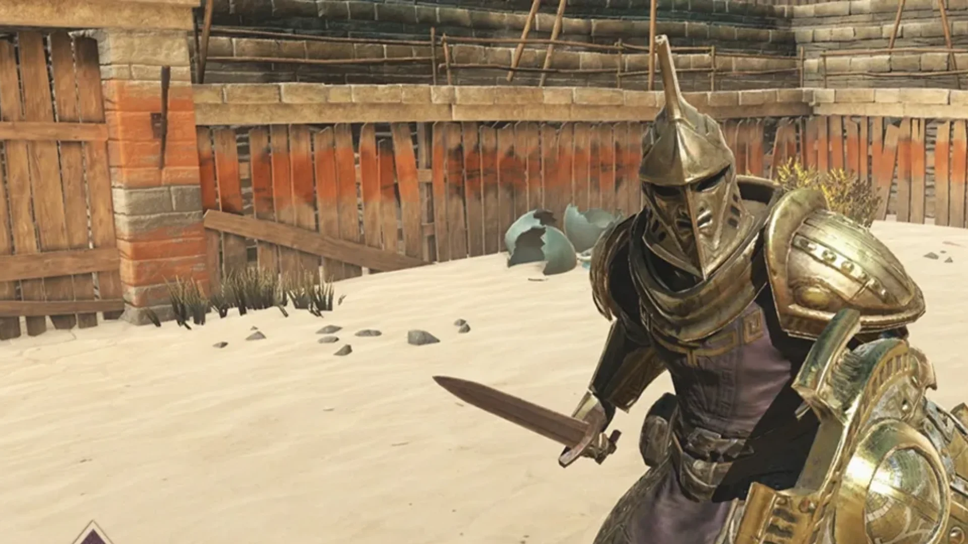 An armored warrior holding a sword and shield stands inside a sandy arena surrounded by wooden fencing.