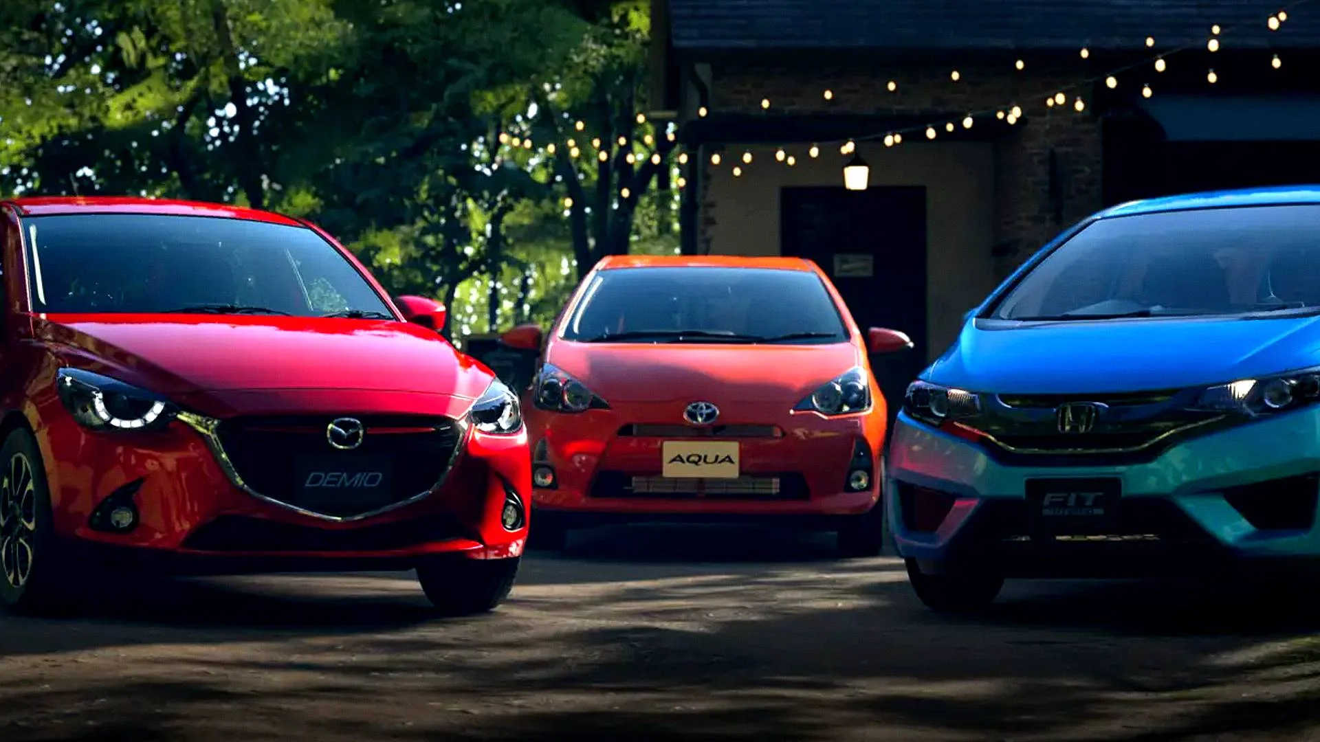 Red Mazda Demio, Toyota Aqua, and blue Honda Fit are parked together in Gran Turismo 7.