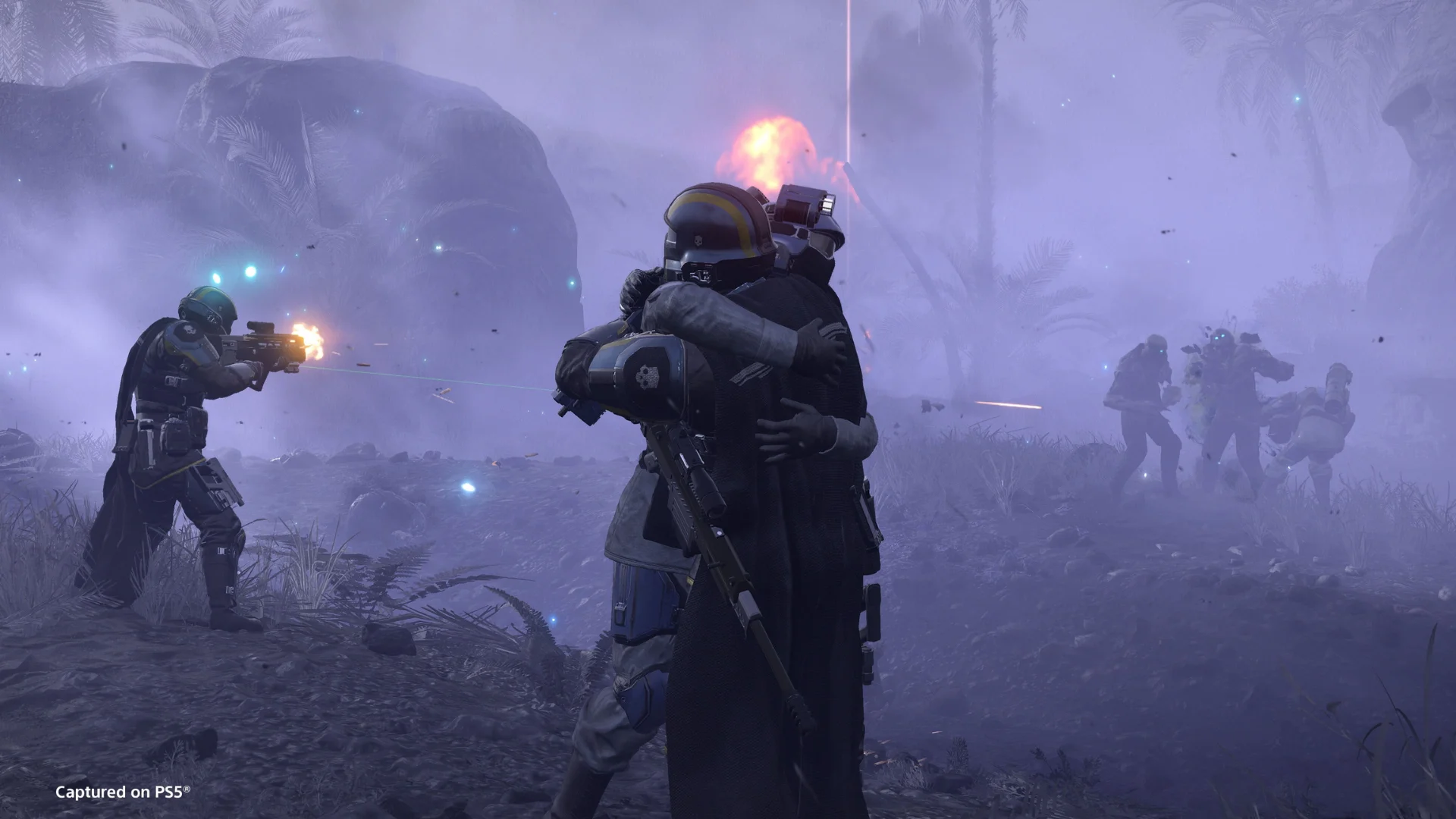 Two Helldivers embrace during a firefight as squadmates battle enemies in a foggy Helldivers 2 environment.