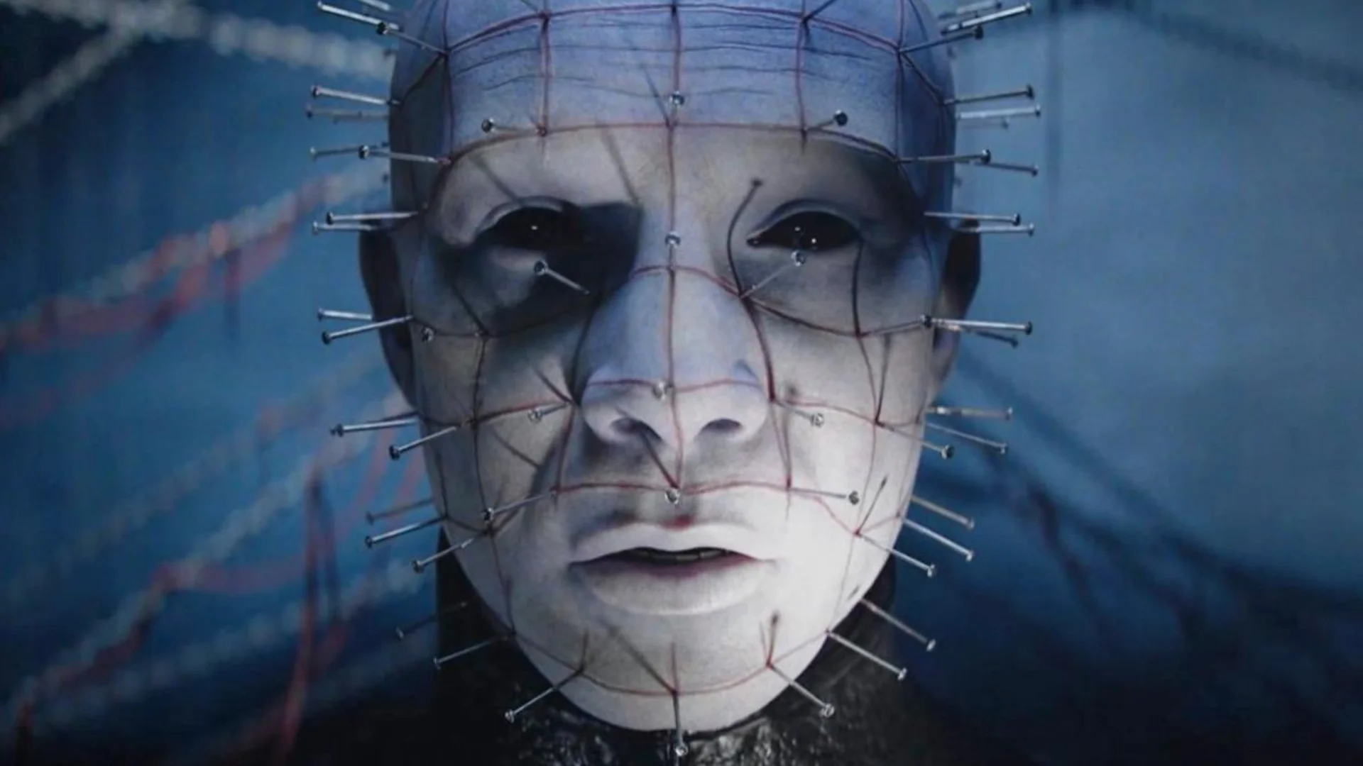A pale Cenobite with pins across its face appears in a close-up scene from Hellraiser: Revival.
