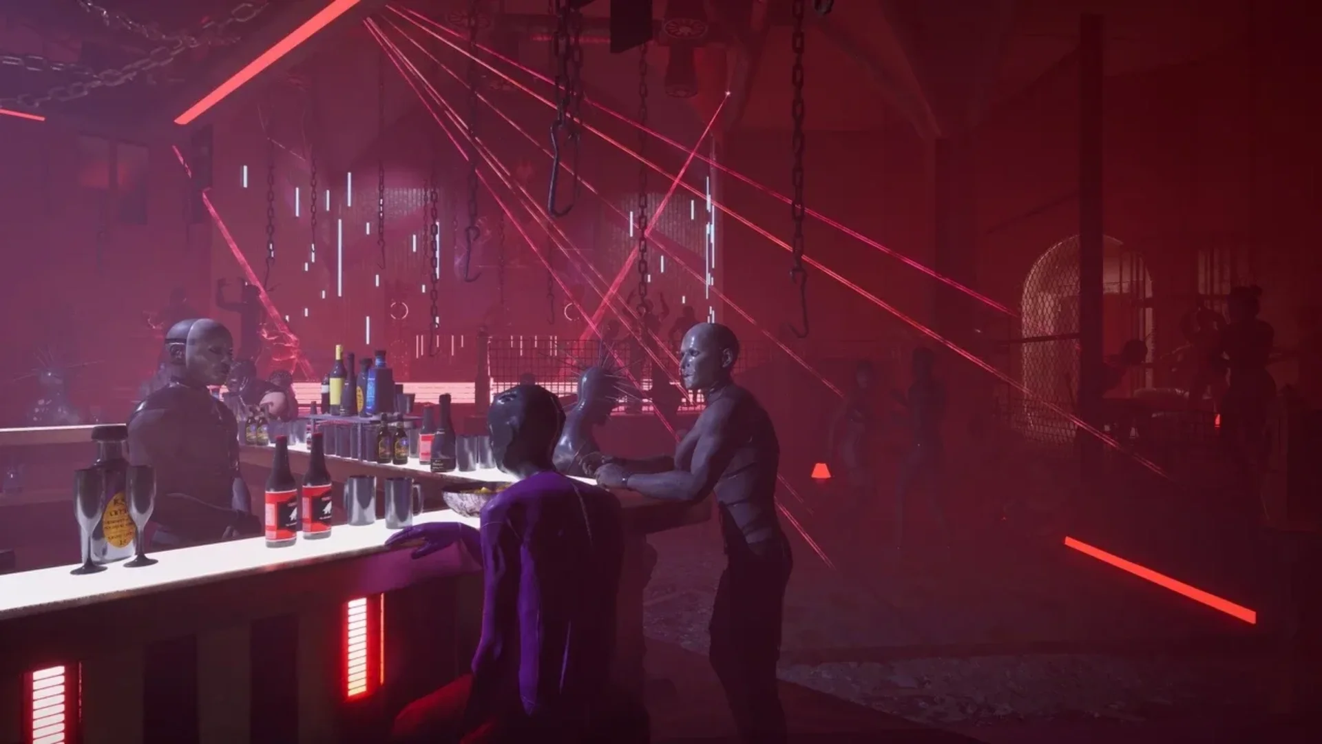Several figures gather around a bar surrounded by chains, hooks, and red lighting in Hellraiser: Revival.